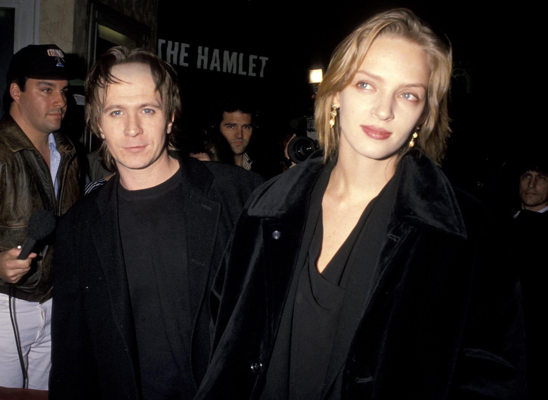 Gary Oldman's spouse, Uma Thurman, walking in front of him at an event