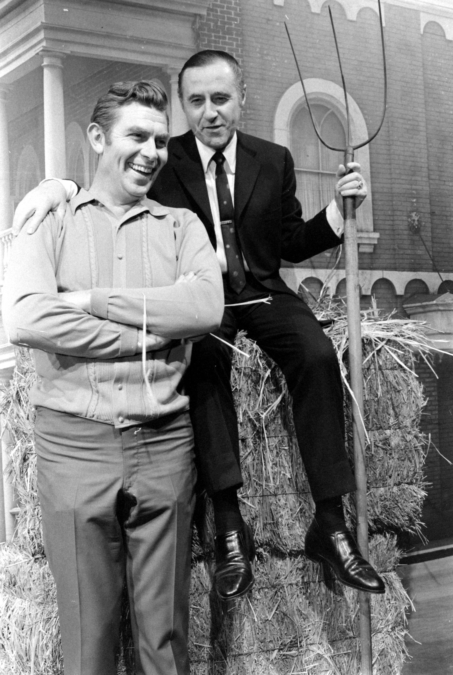 Actor Andy Griffith and his manager/producer Richard Linke pose for a photo as they sit on bales of hay, 1969