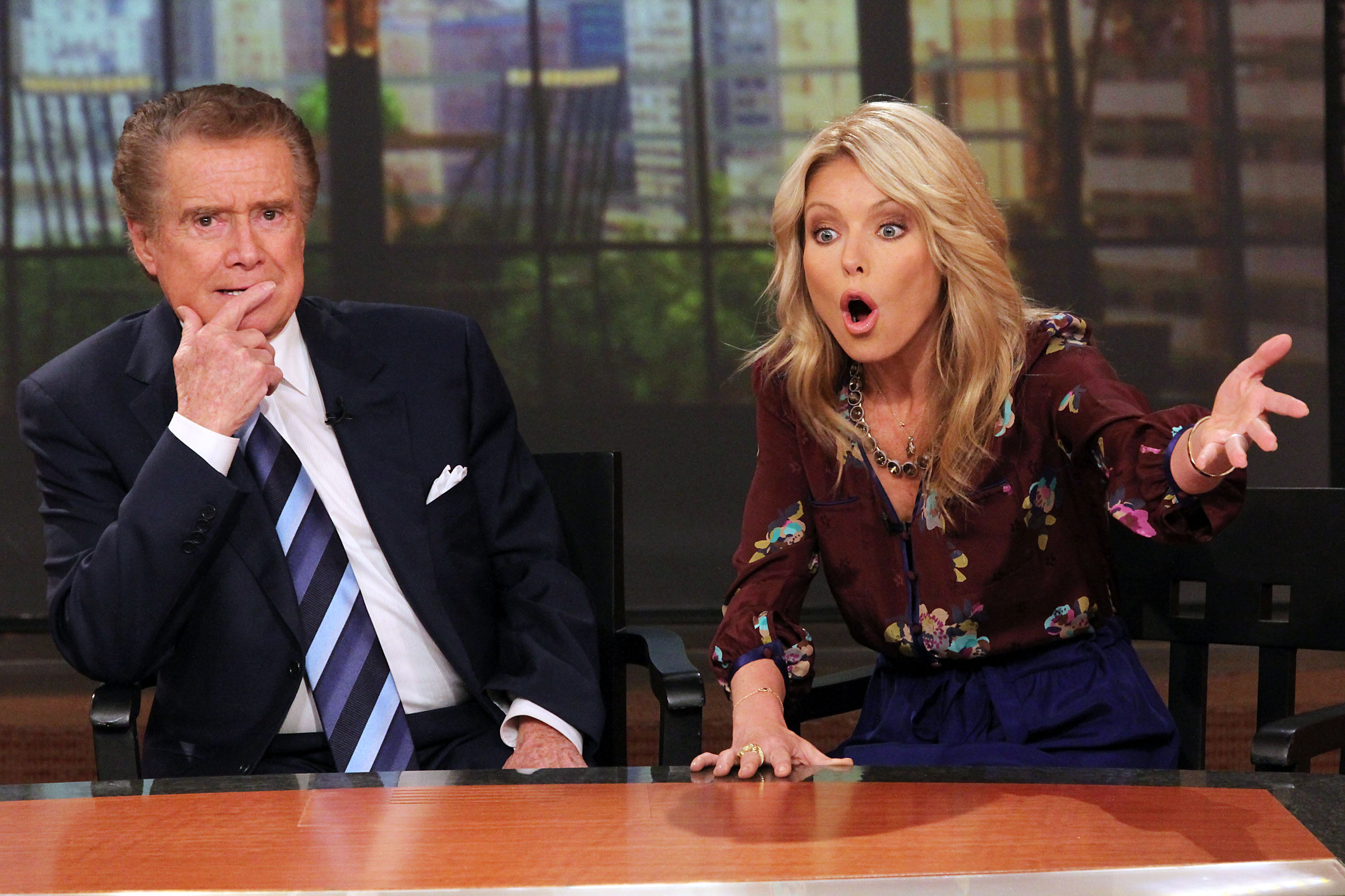 'Live with Regis and Kelly' stars Regis Philbin and Kelly Ripa appear together at a 2011 press conference announcing Philbin's departure from the long-running morning show. In the photo, Ripa is speaking while gesturing with her hand.