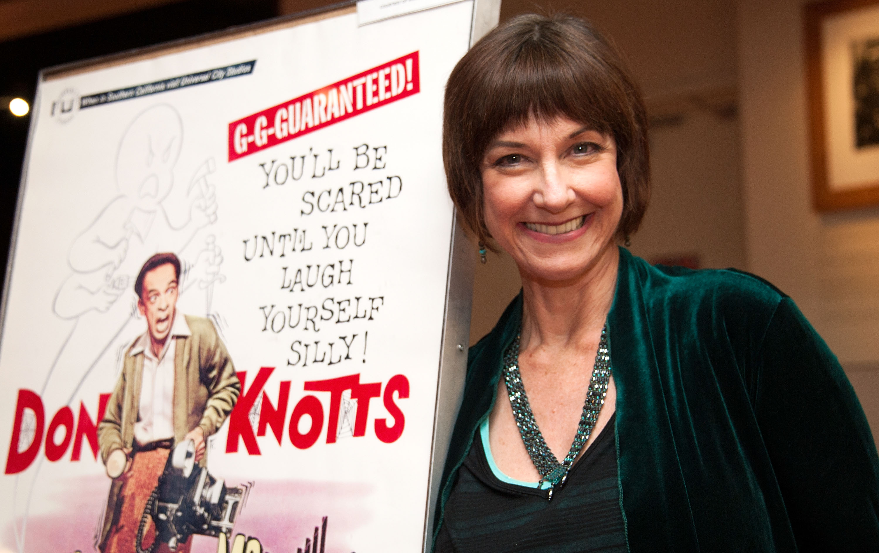 Actor Karen Knotts, daughter of Don Knotts, poses in front of a promotional poster for her father's 1966 film, 'The Ghost and Mr. Chicken', 2012