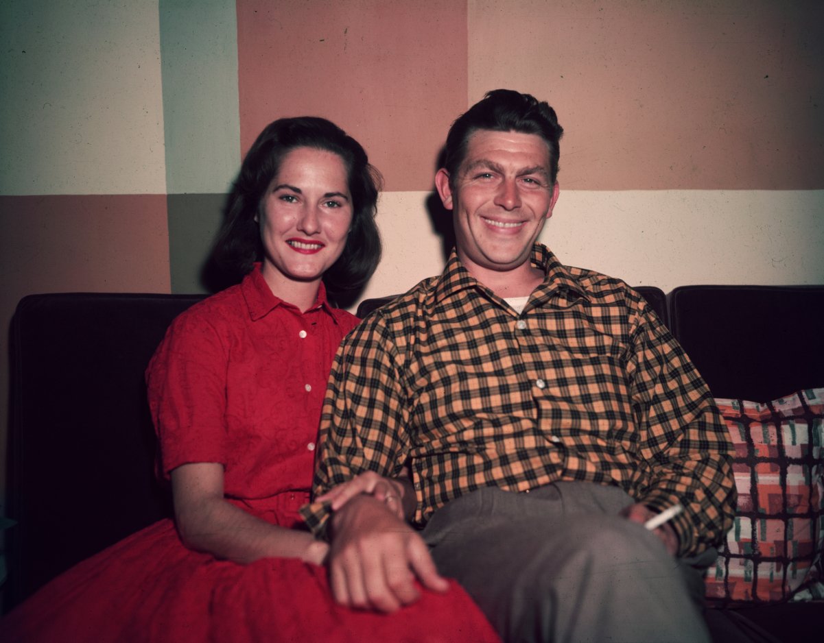 Andy Griffith sits on a sofa with his first wife, Barbara Edwards, and holds a cigarette, 1960s. He has his hand over her knee.