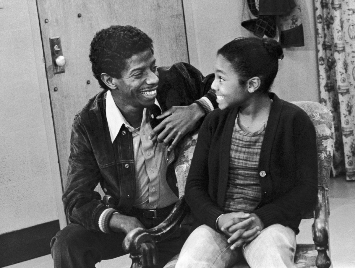 American actor and comedian Jimmie Walker smiles as he speaks to child actor and singer Janet Jackson in a still from an episode of the television series 'Good Times,' 1978