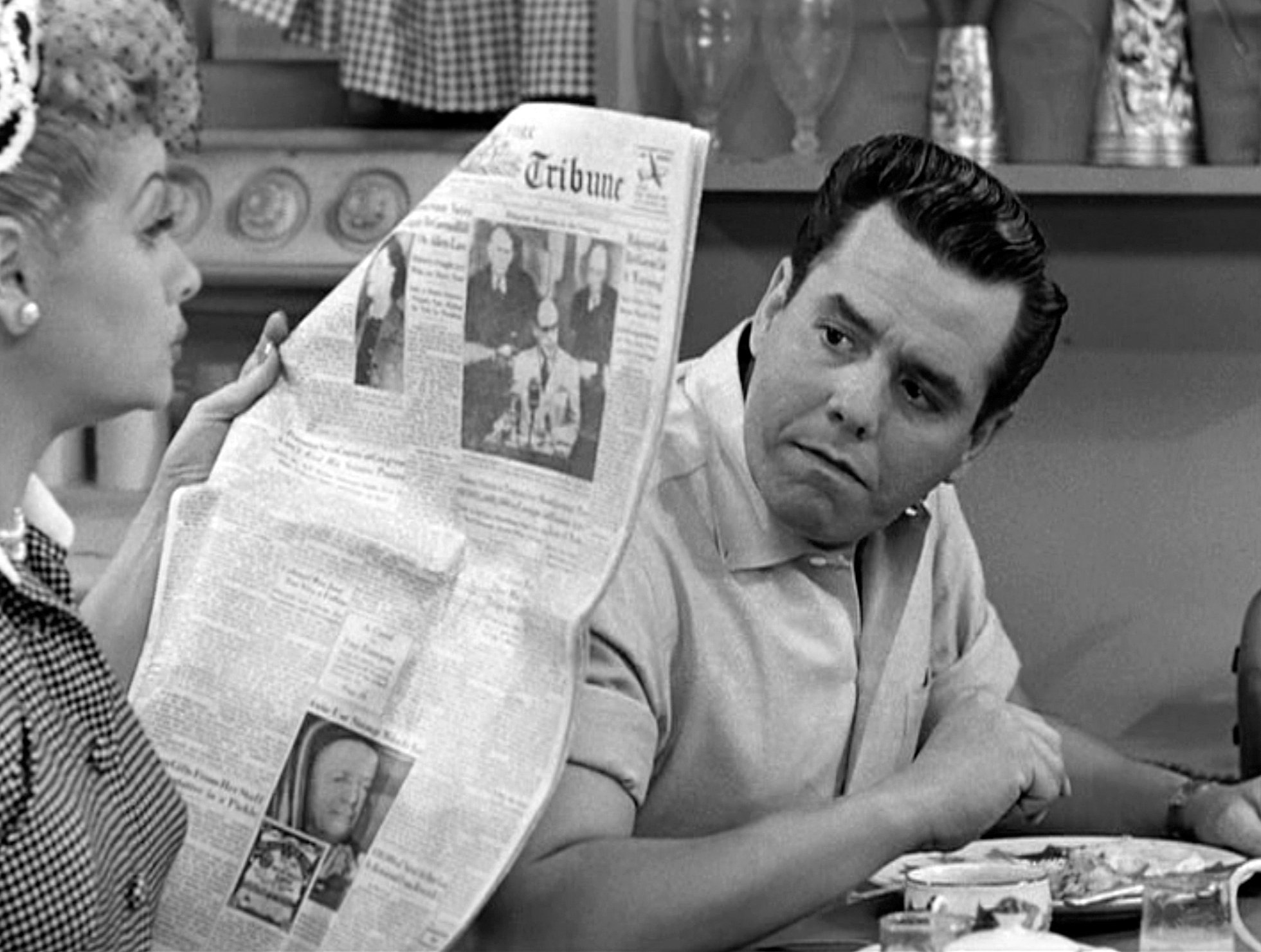 In a scene from the ‘Job Switching’ episode of 'I Love Lucy,' Lucille Ball reads a newspaper while co-star and husband Desi Arnaz looks on, 1952