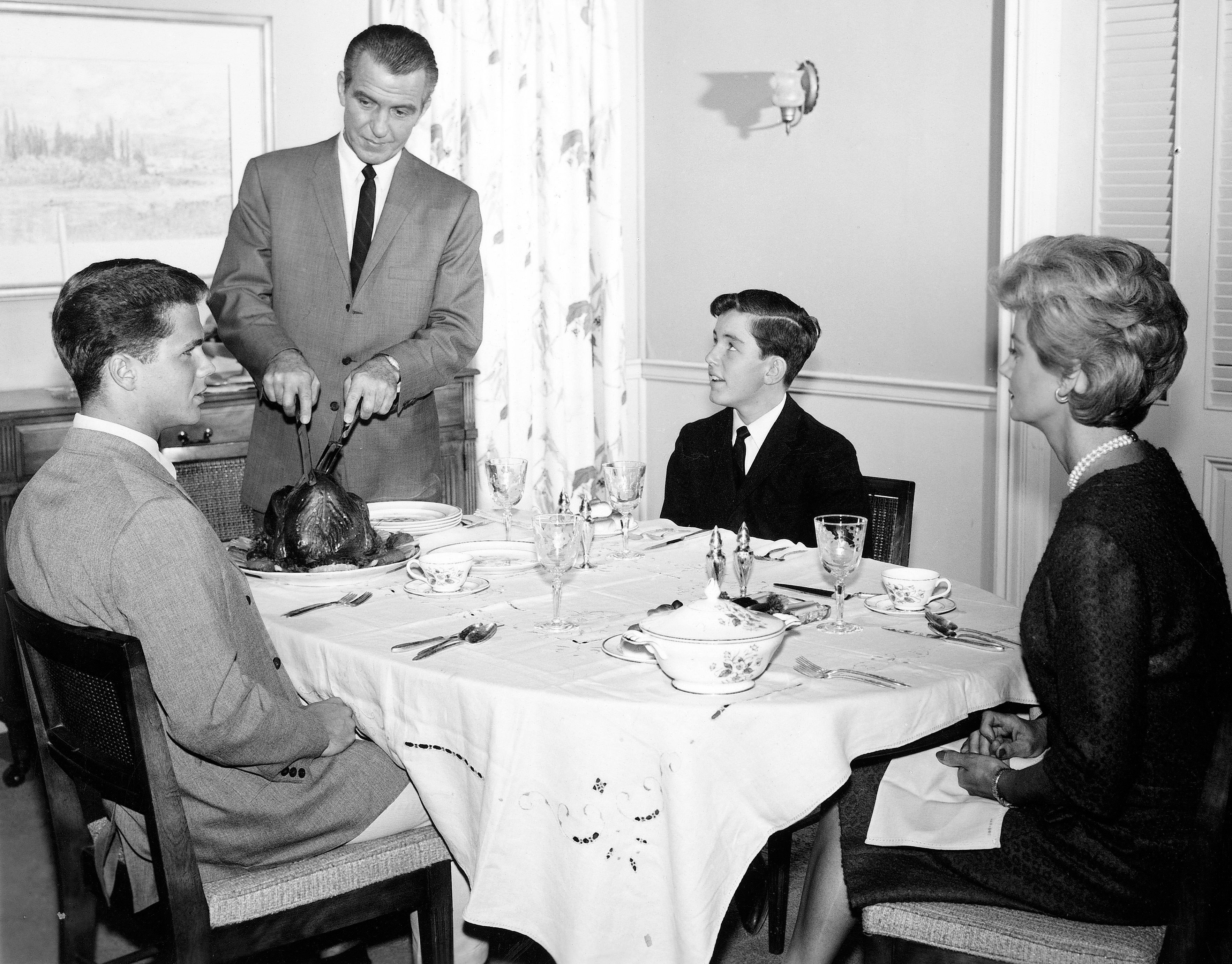 The cast of 'Leave It to Beaver' in a dinnertime scene. Seen are, clockwise, Hugh Beaumont (standing) as Ward Cleaver, Jerry Mathers as Beaver Cleaver, Barbara Billingsley as June Cleaver, and Tony Dow as Wally Cleaver