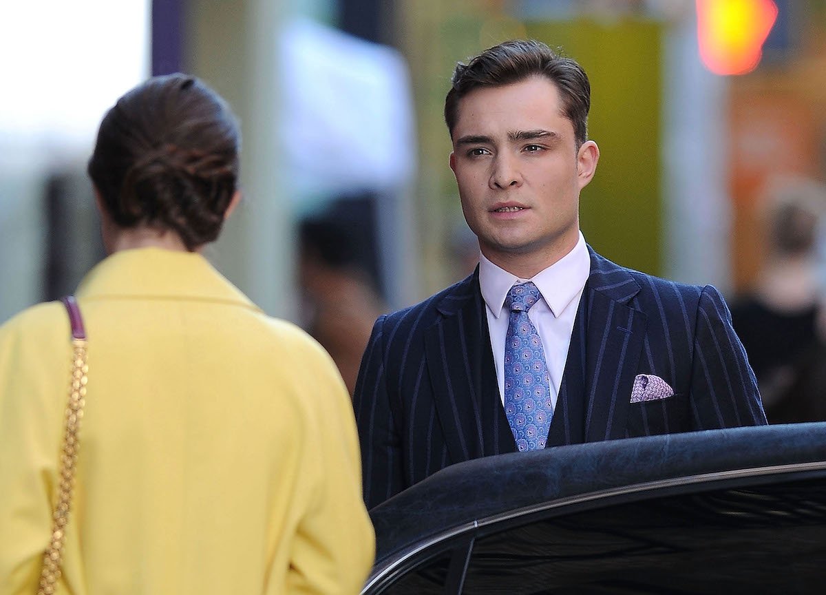 Ed Westwick as Chuck Bass is by a car standing on the street in a suit "Gossip Girl"