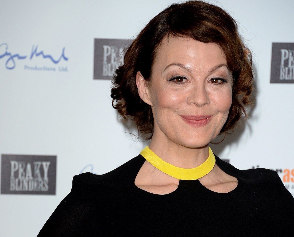 Helen McCrory smiles softly at the camera in a black dress for the Peaky Blinders photo call