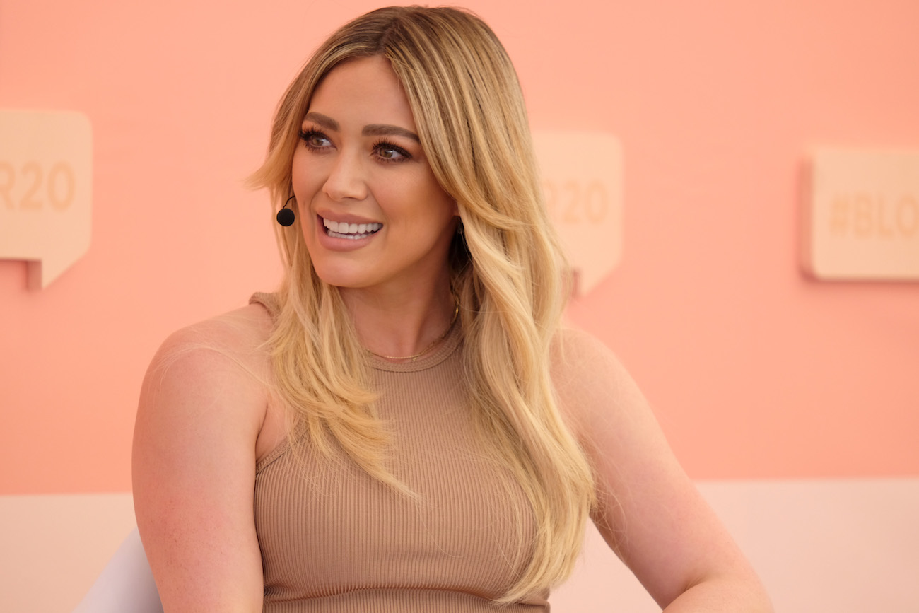 Hilary Duff sitting in front of beige background