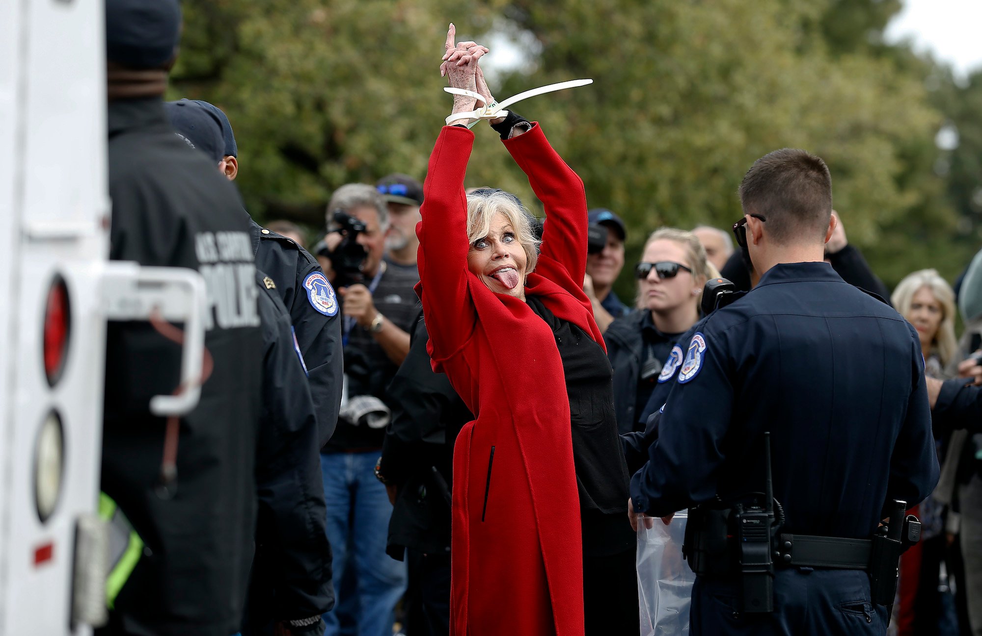 Jane Fonda, hands zip tied, sticking her tongue out at the camera