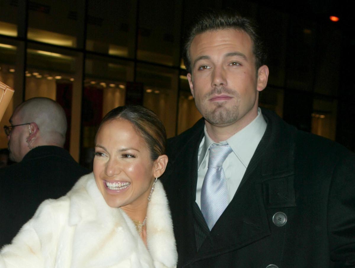 Jennifer Lopez smiling in a white coat with Ben Affleck looking into the camera