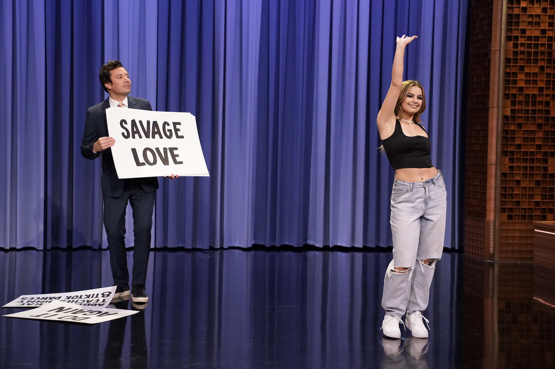 Addison Rae on the stage of 'The Tonight Show Starring Jimmy Fallon' with Jimmy Fallon in the background. Addison Rae's net worth is impressive thanks to her TikTok fame