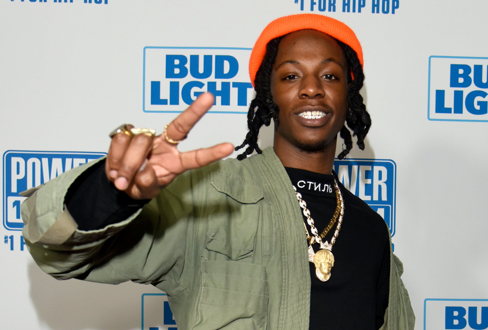 Joey Bada$$ holding up a peace sign in front of a white background