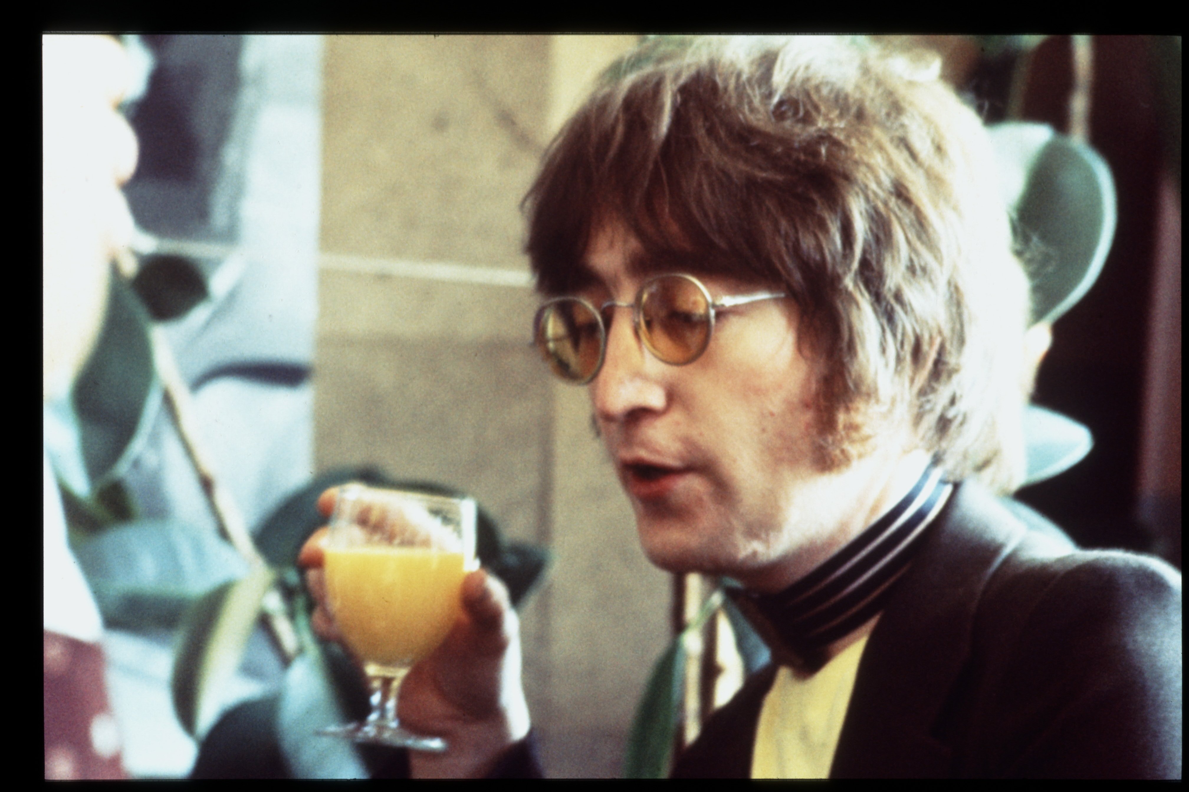 John Lennon holding a glass of orange juice