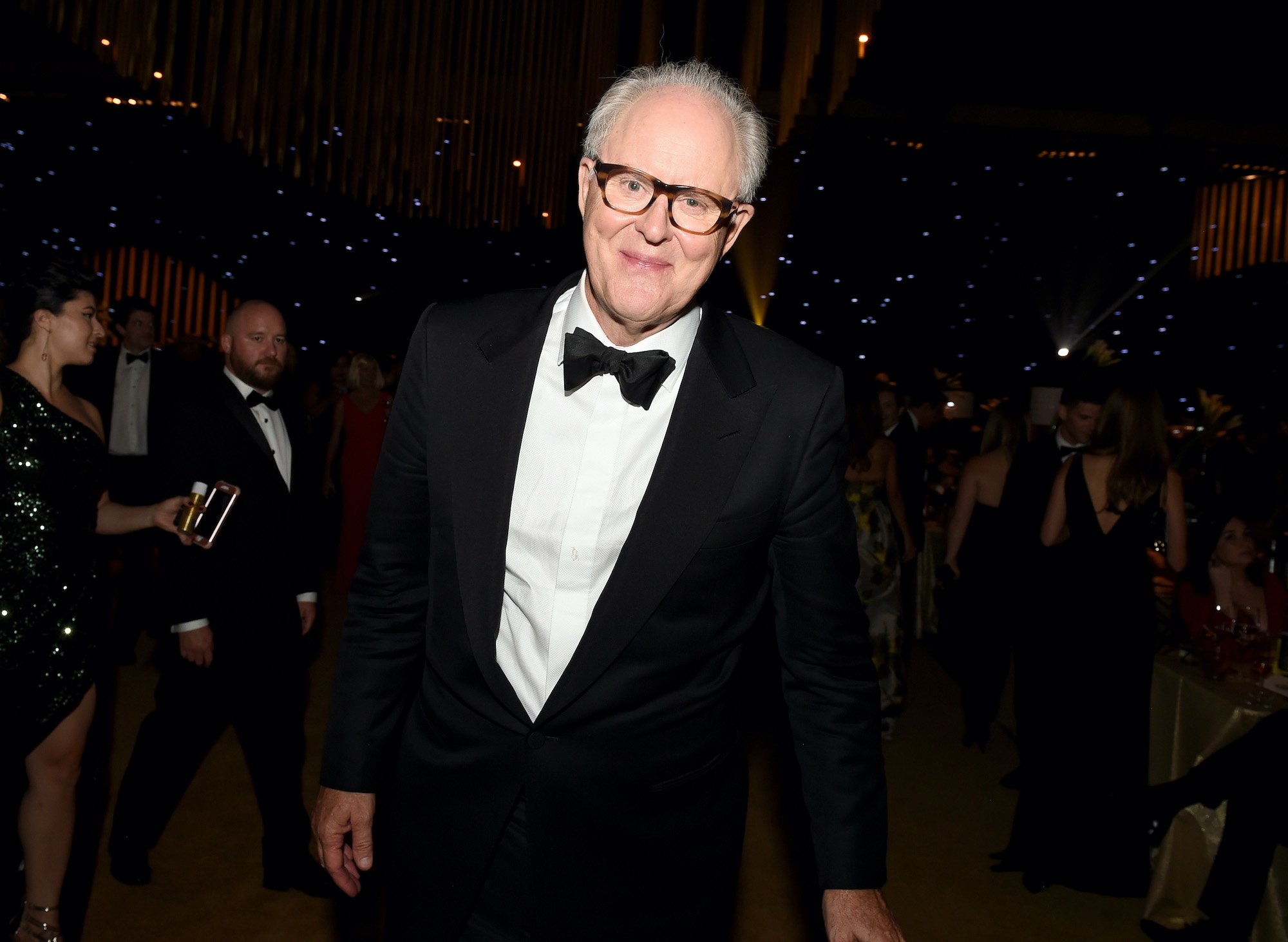 John Lithgow smiling in front of a theater full of people