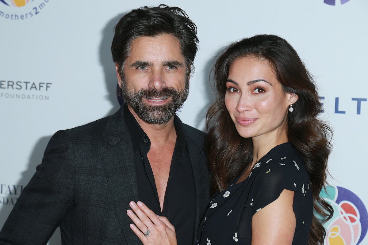 John Stamos and Caitlin McHugh dressed in black smile for the camera