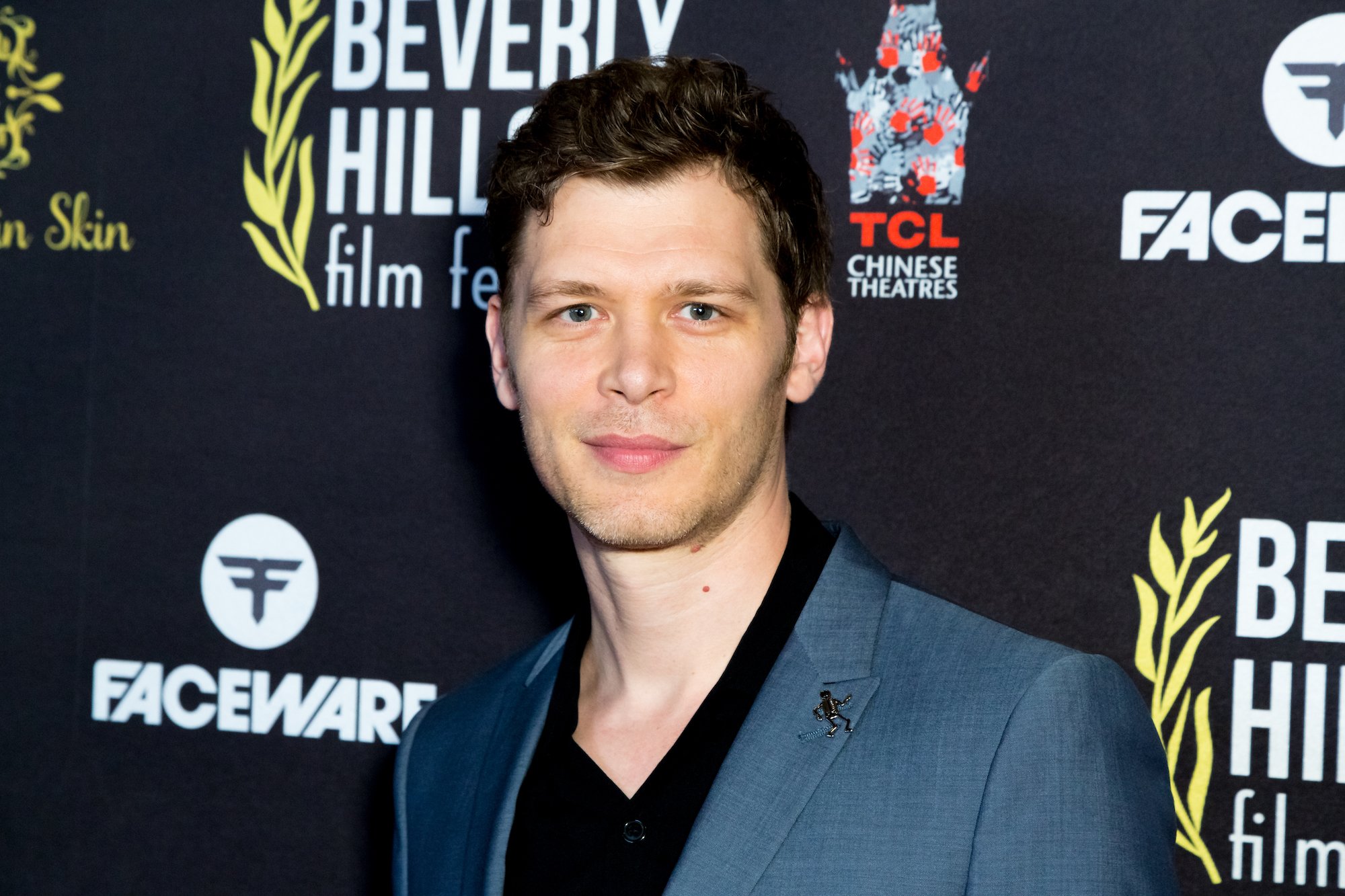 Joseph Morgan smiling in front of a black background