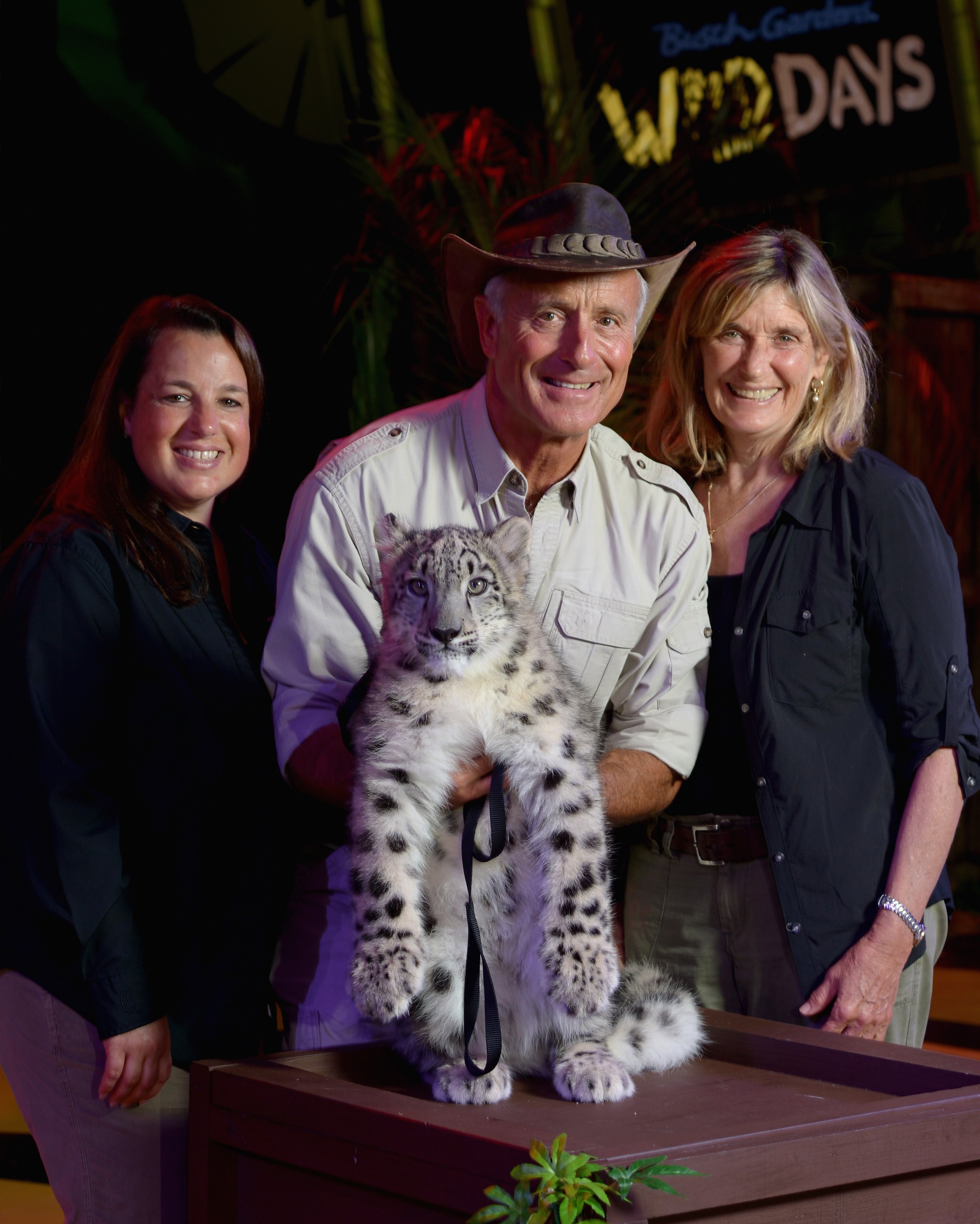 Jungle Jack Hanna standing with his wife and their daughter, Julie, as they pose with an endangered Snow Leopard
