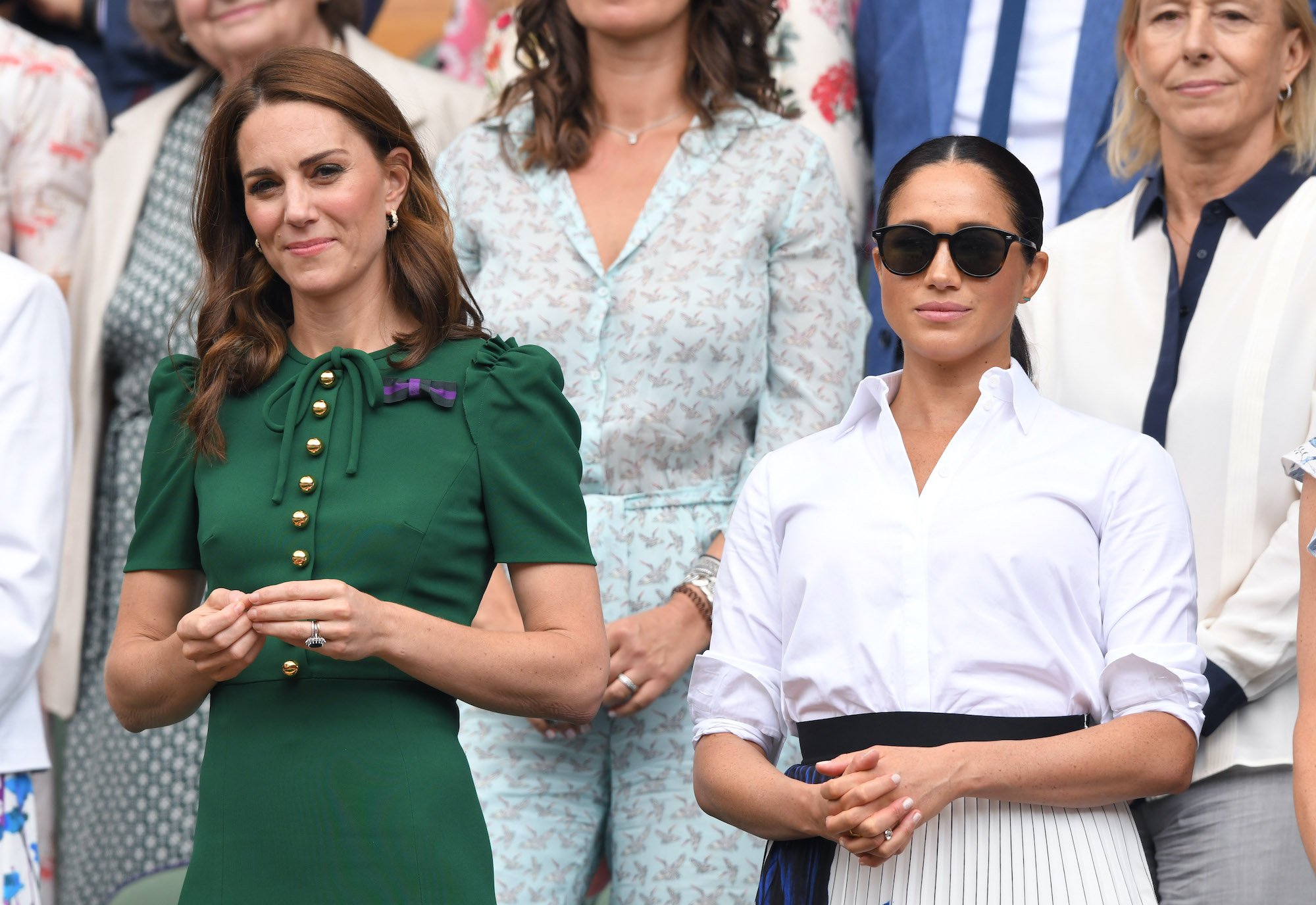 (L-R) Kate Middleton and Meghan Markle, standing in front of a crowd