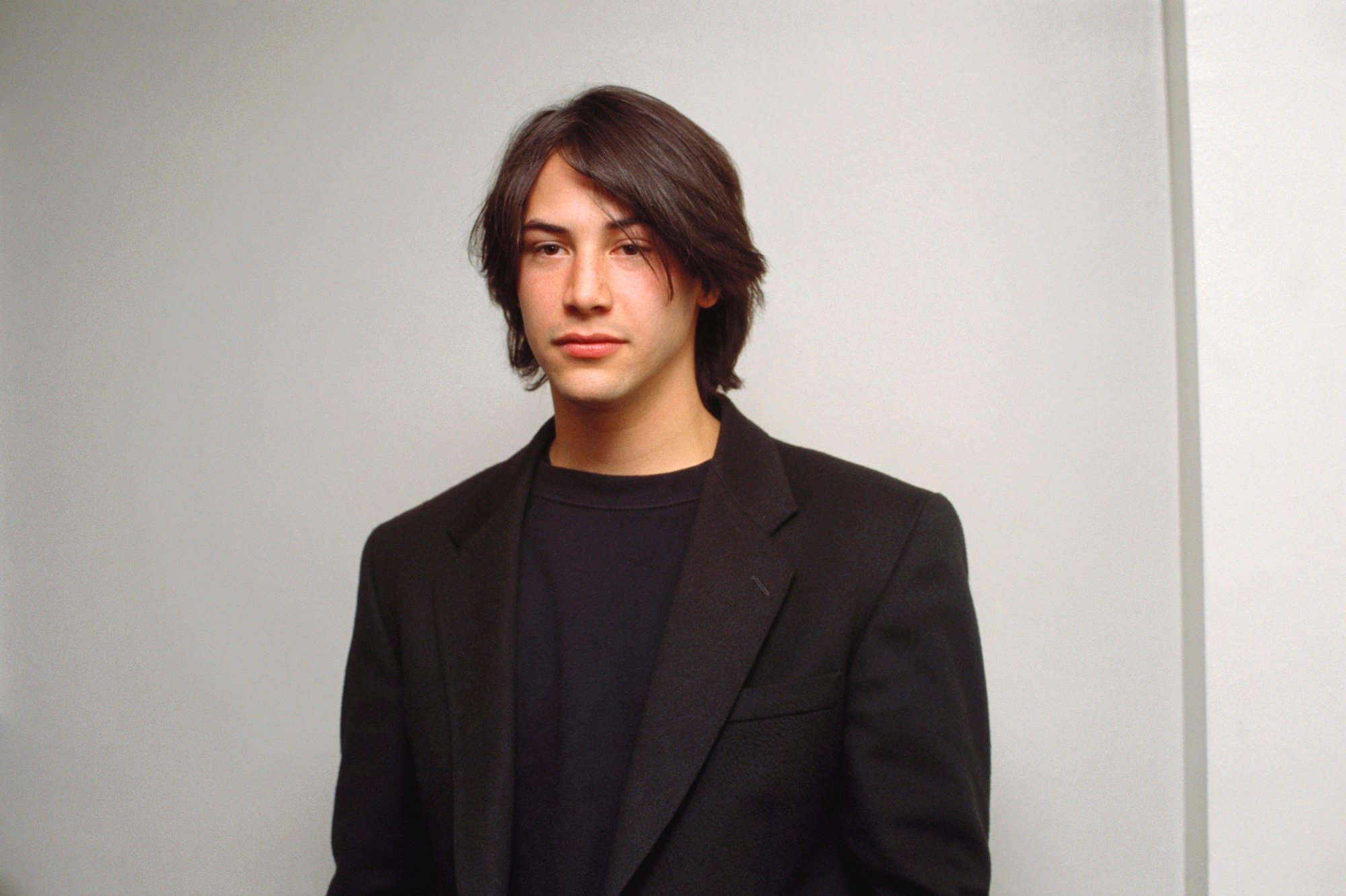 Keanu Reeves looking serious in a black suit