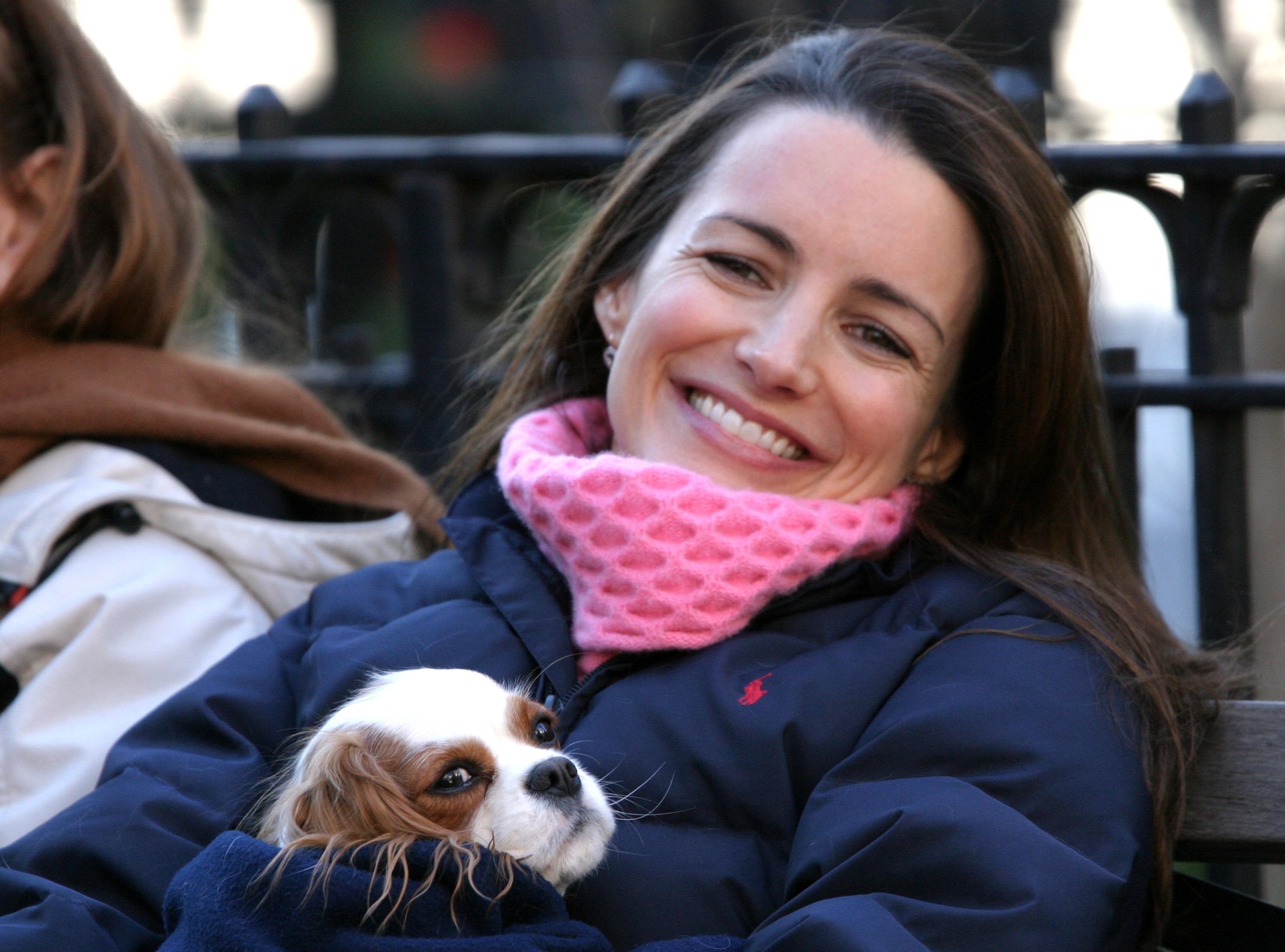Kristin Davis sits at the 23rd and Broadway Dogwalk holding a Cavalier King Charles Spaniel during a scene for 'Sex and the City' in 2003