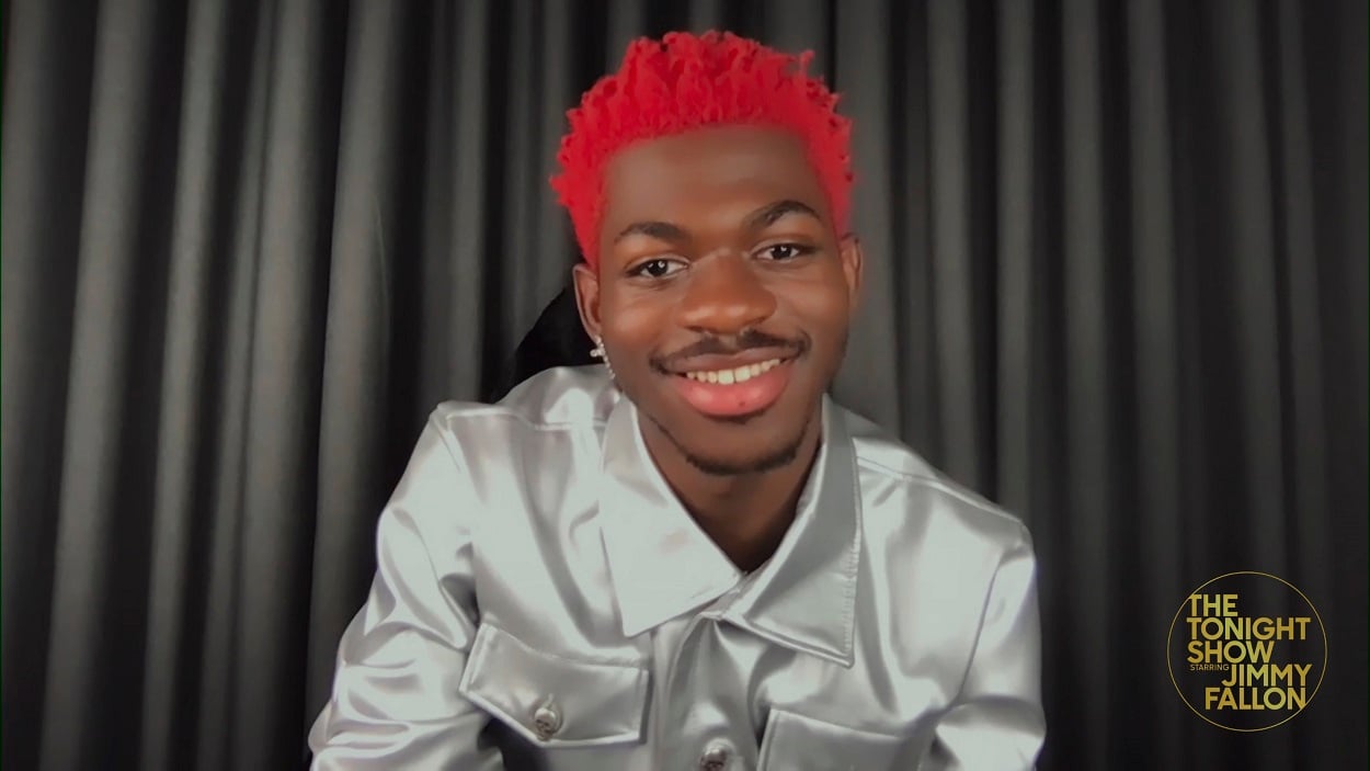 Lil Nas X sporting red hair smiles at the camera during a recording of The Tonight Show Starring Jimmy Fallon