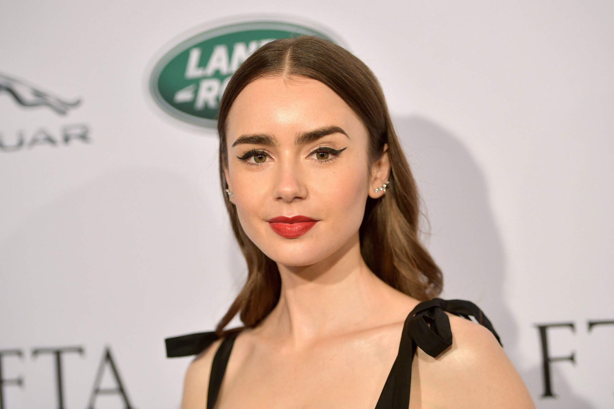 Lily Collins smiling in front of a white background