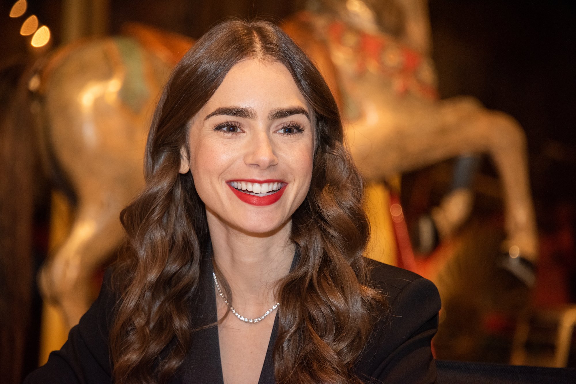 Lily Collins smiling in front of a blurred background