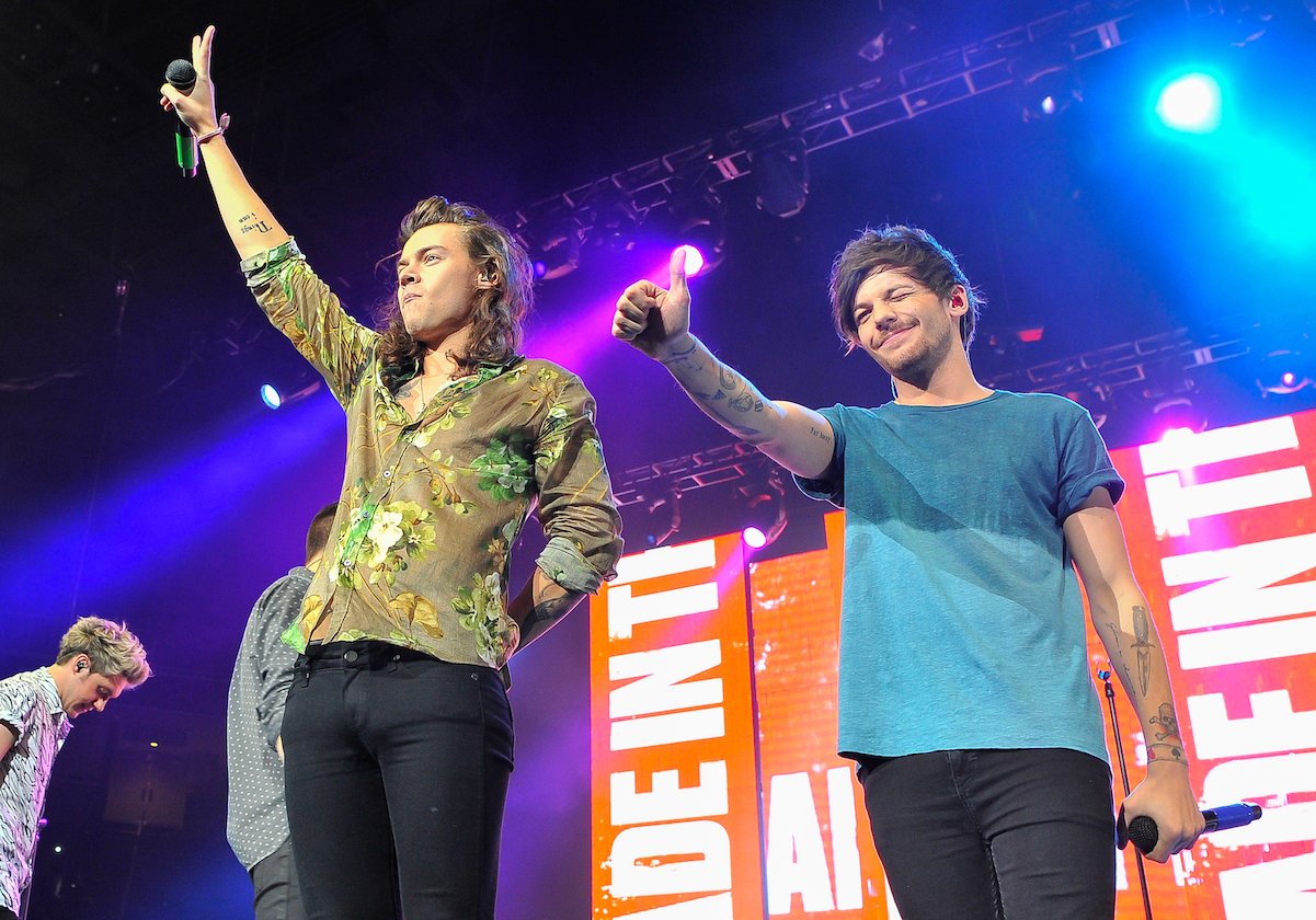 Louis Tomlinson in a blue shirt and Harry Styles in a green shirt for a One Direction performance