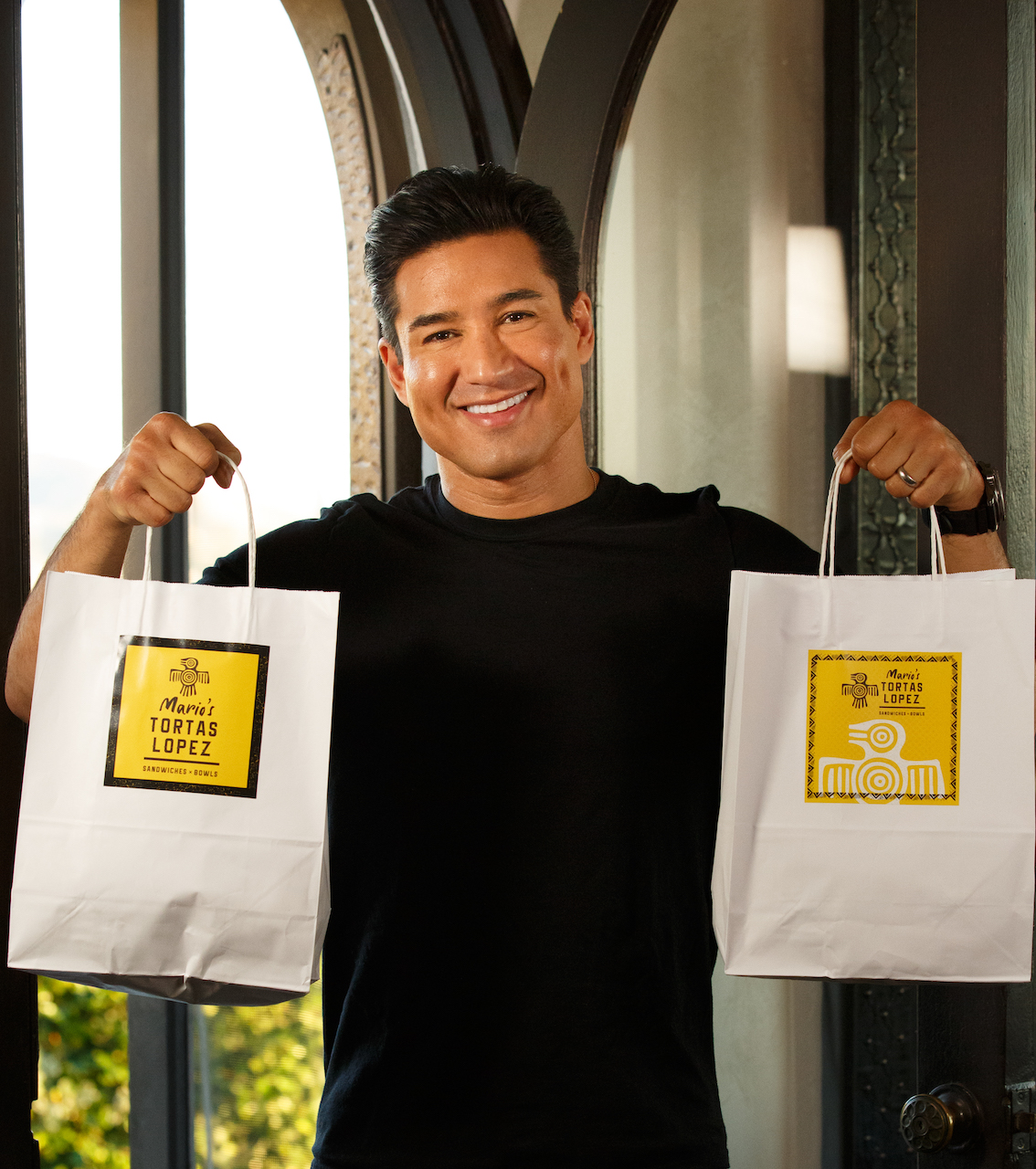 Mario Lopez holding to-go bags from his restaurant Mario Tortas Lopez