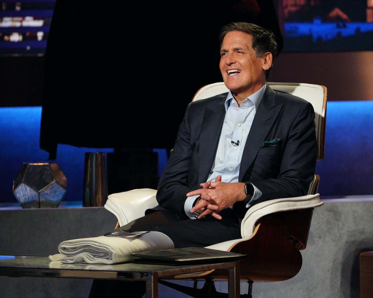 Mark Cuban smiling in a dark jacket on the panel of 'Shark Tank' 