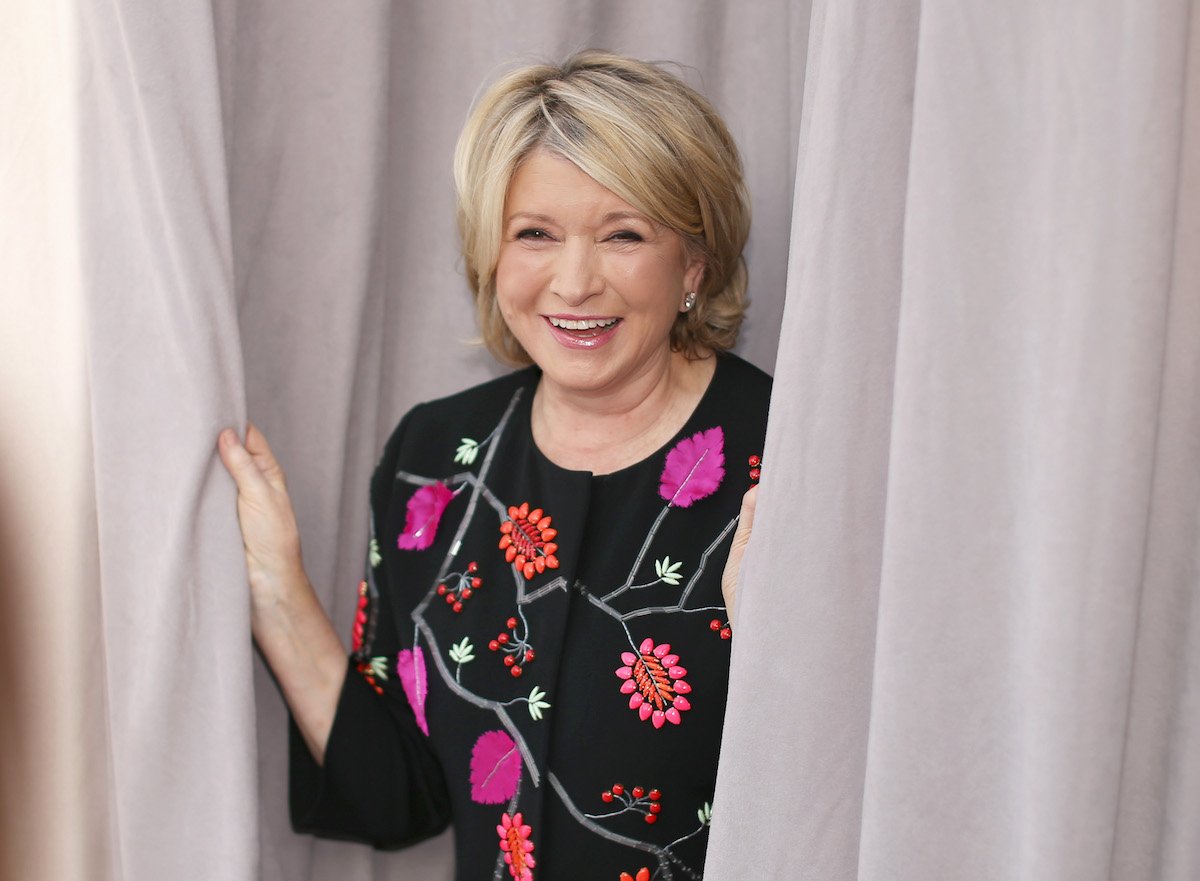 Martha Stewart smiles and holds some curtains