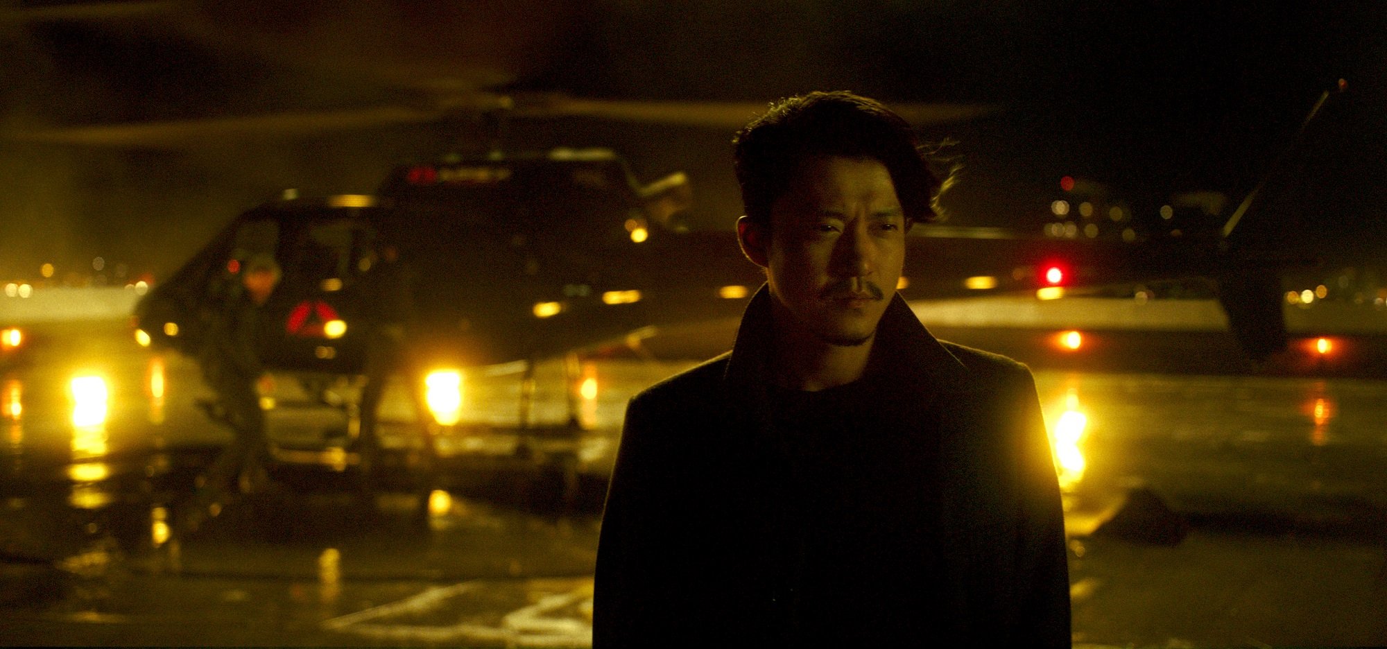 MechaGodzilla pilot Shun Oguri stands at an airfield at night