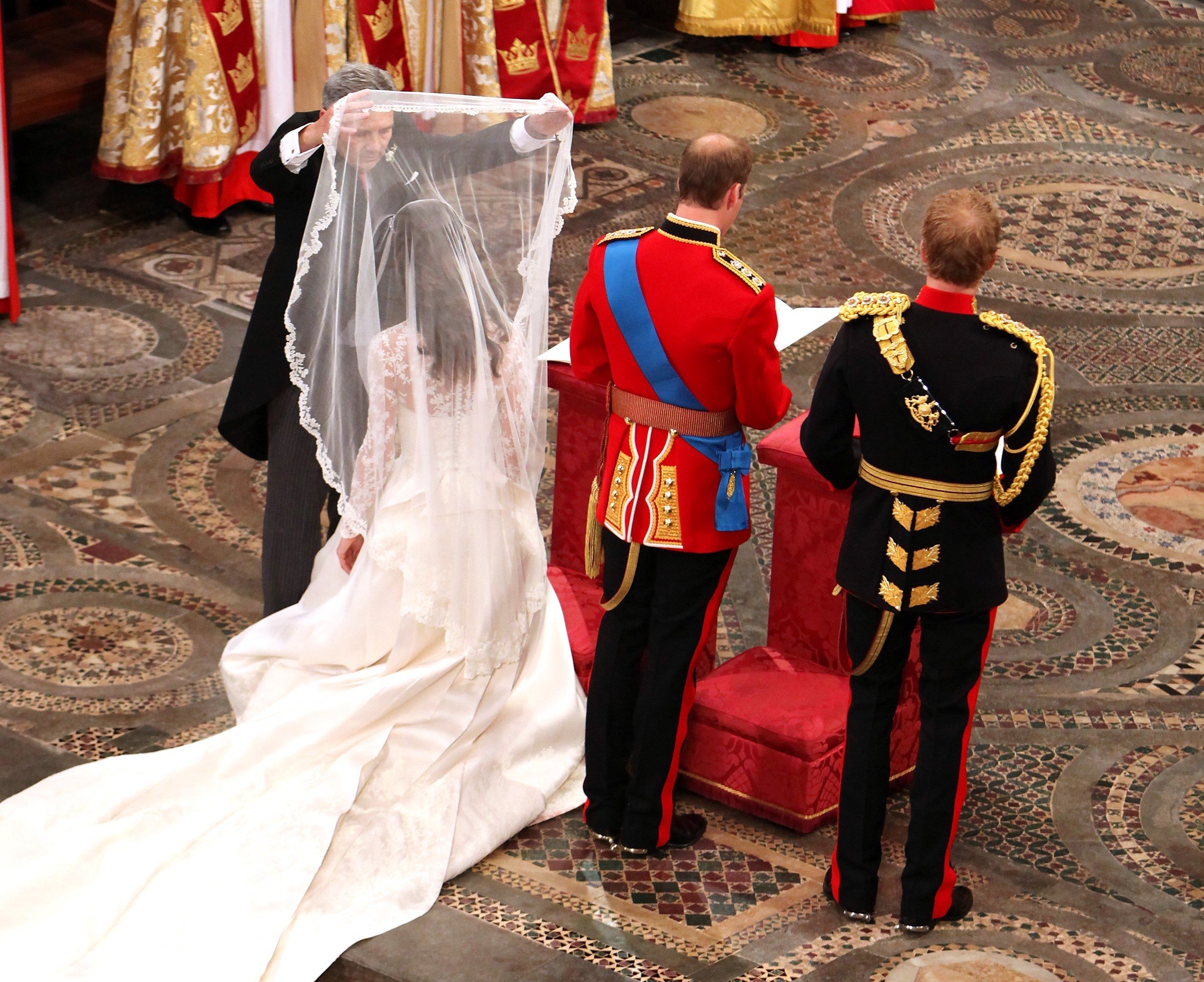 Michael Middleton lifts the bridal veil from Kate Middleton's face at the commencement of her wedding ceremony to Prince William as Prince Harry looks on
