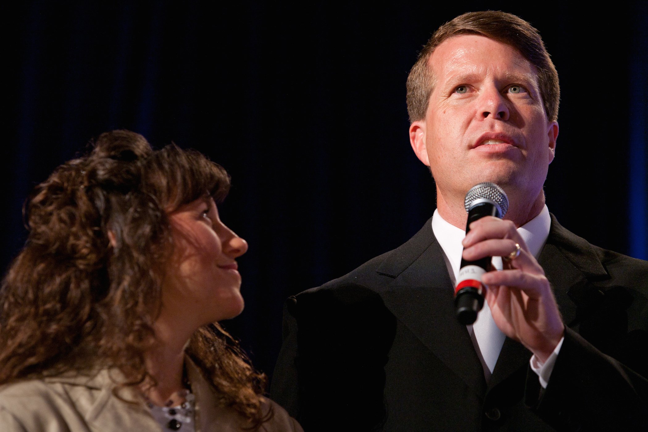 Duggar family member from 'Counting On' Michelle Duggar looking up at Jim Bob Duggar as he speaks into a microphone