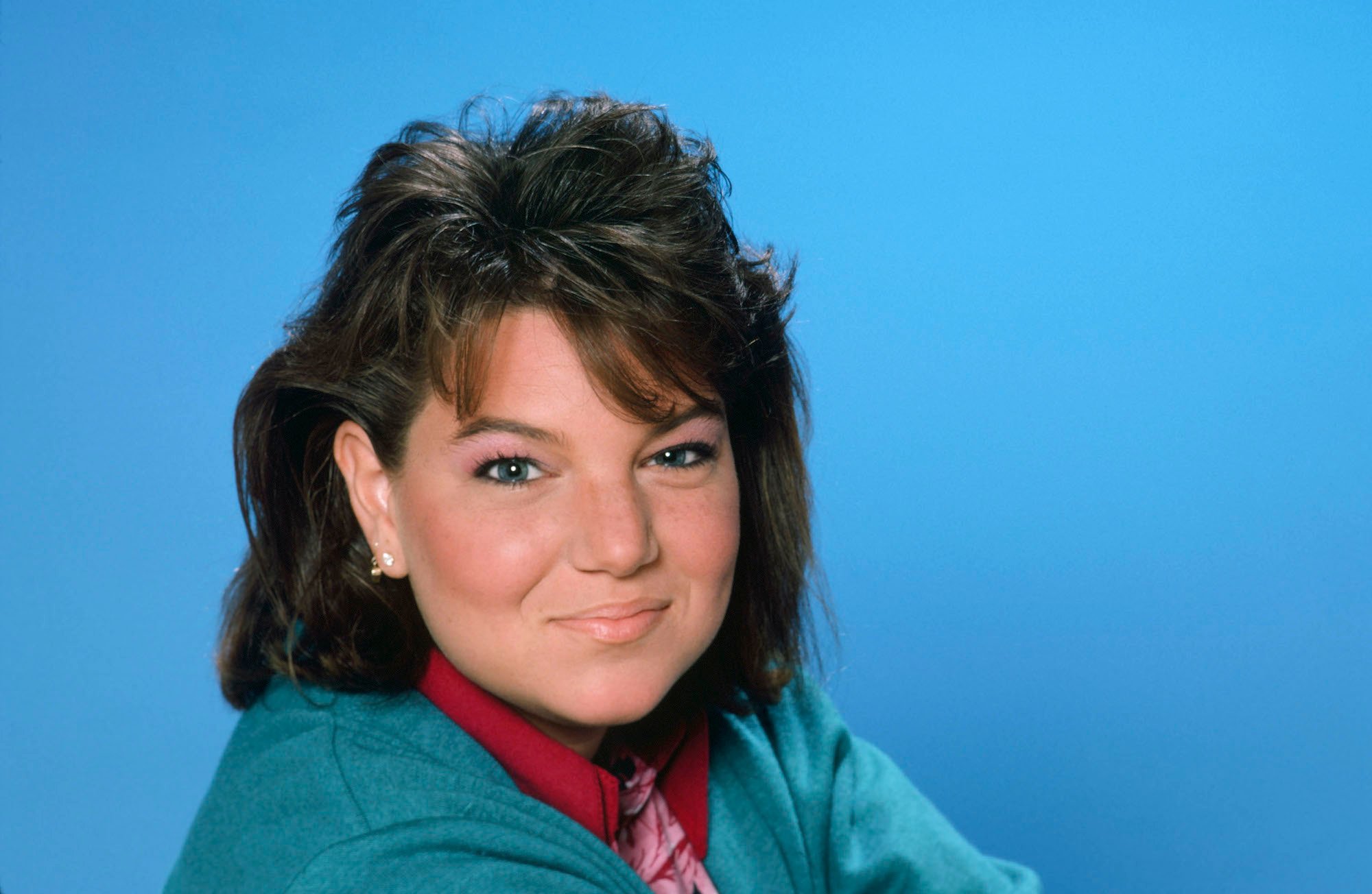 Mindy Cohn smiling in front of a blue background