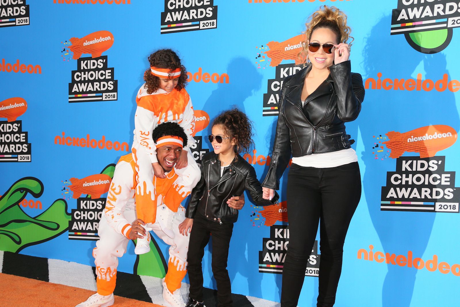 Nick Cannon's kids standing at an awards show with Mariah Carey. Nick Cannon's son is on his shoulders while his daughter is next to him