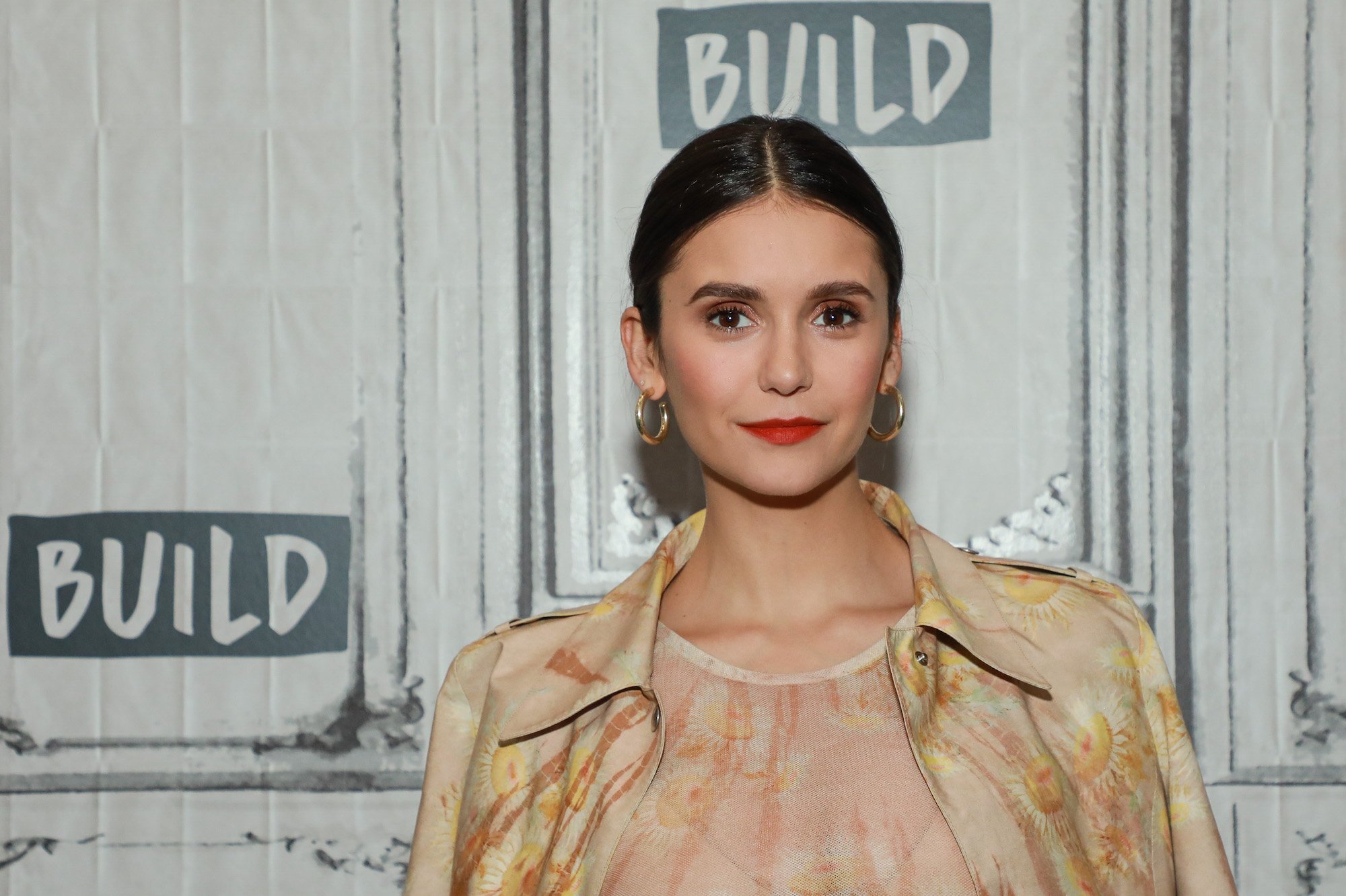 Nina Dobrev smiing in front of a white background