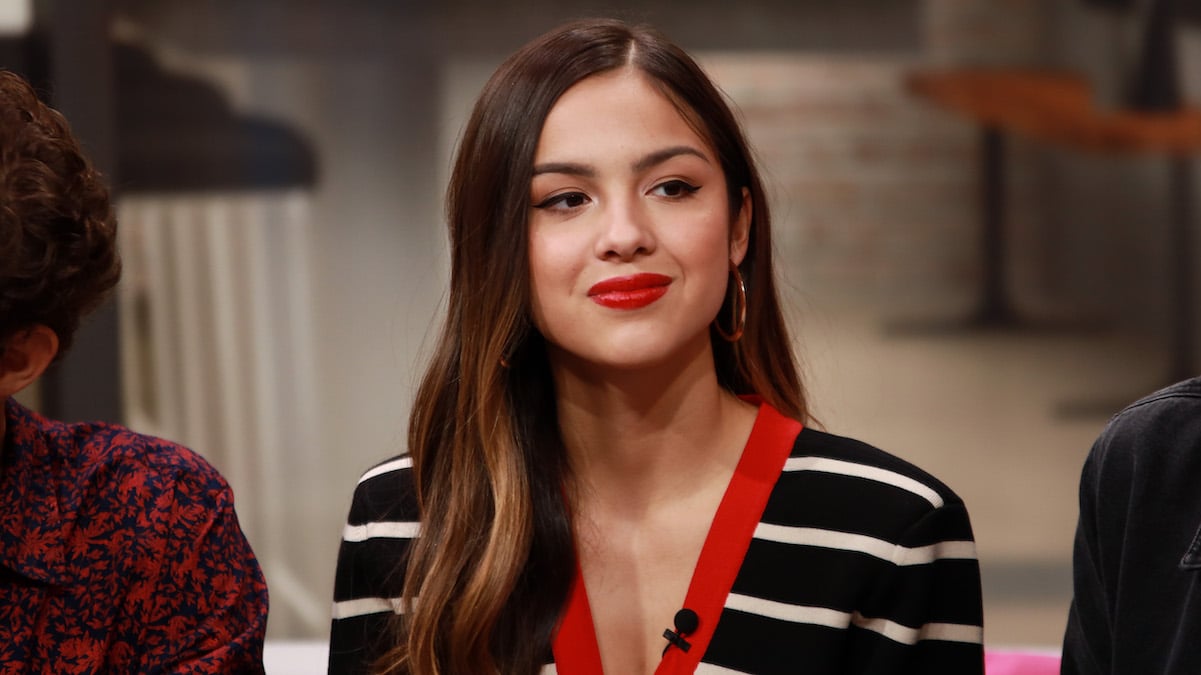 Olivia Rodrigo smiles in a striped sweater during an interview