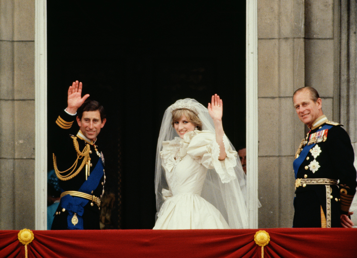 Prince Charles and Princess Diana wave from the balcony of Buckingham Palace following their royal wedding as Prince Philip stands next to them royal wedding