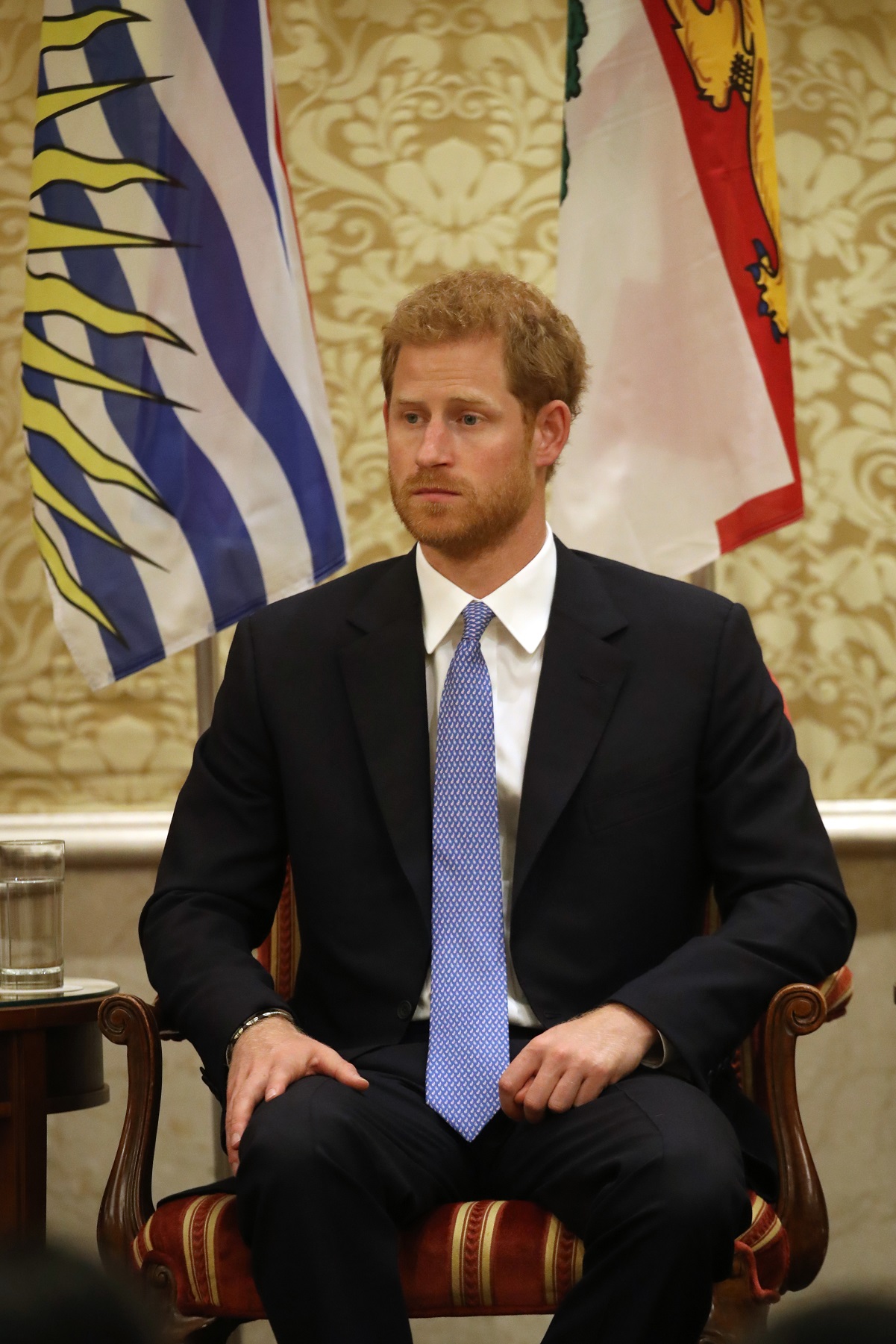 Prince Harry dressed in a dark suit and light blue tie sitting on stage during The Duke Edinburgh's International Gold Award Winners Ceremony