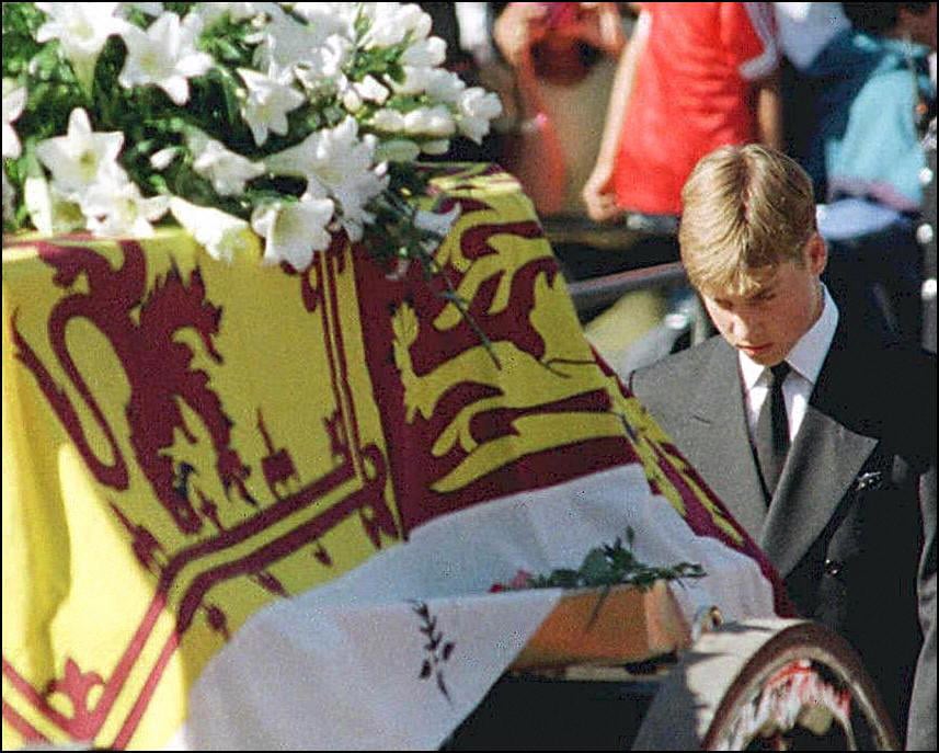 Prince William walks with his head bowed behind the coffin of his mother