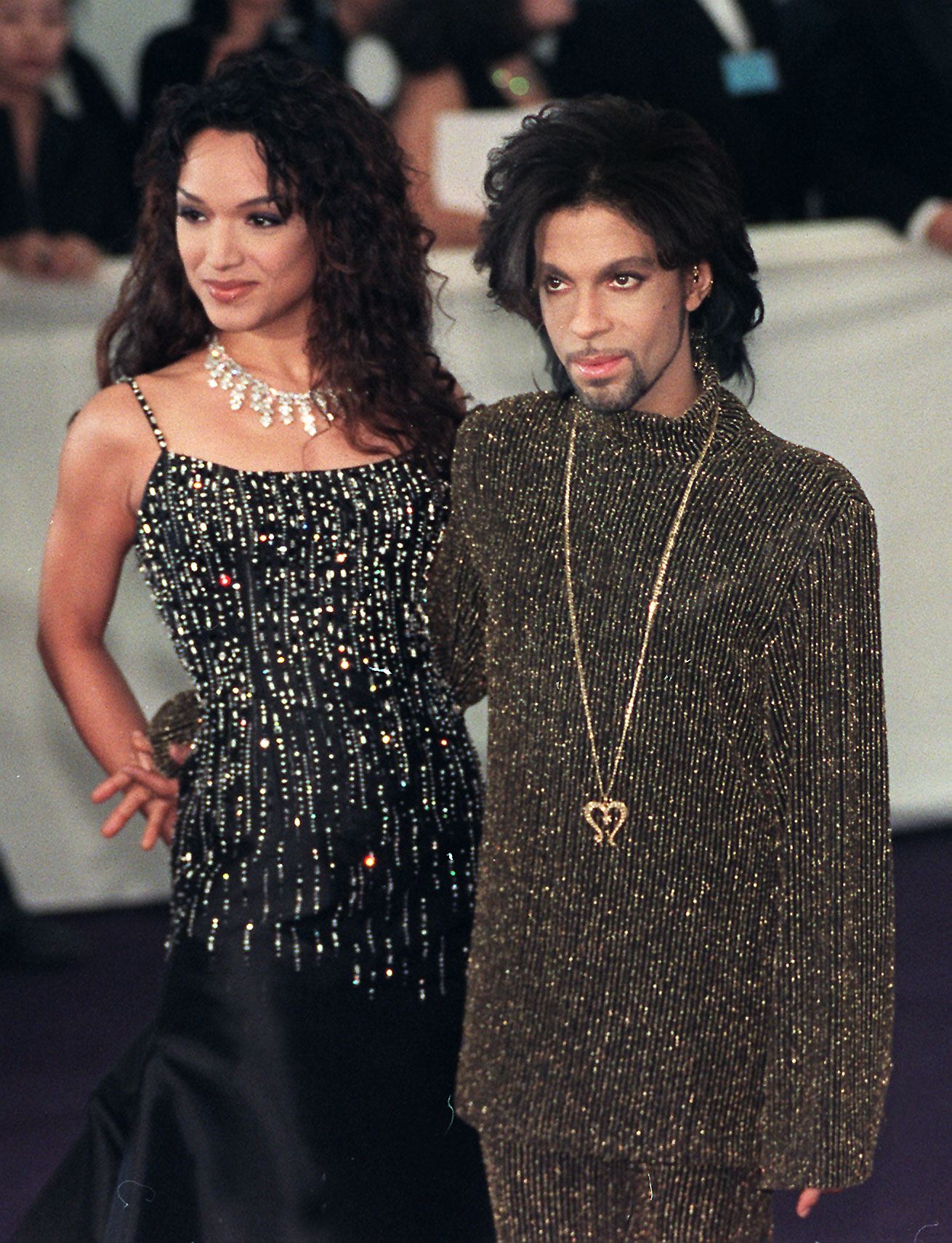 Prince poses with his arm around his wife, Mayte, at a charity fashion show in 1999