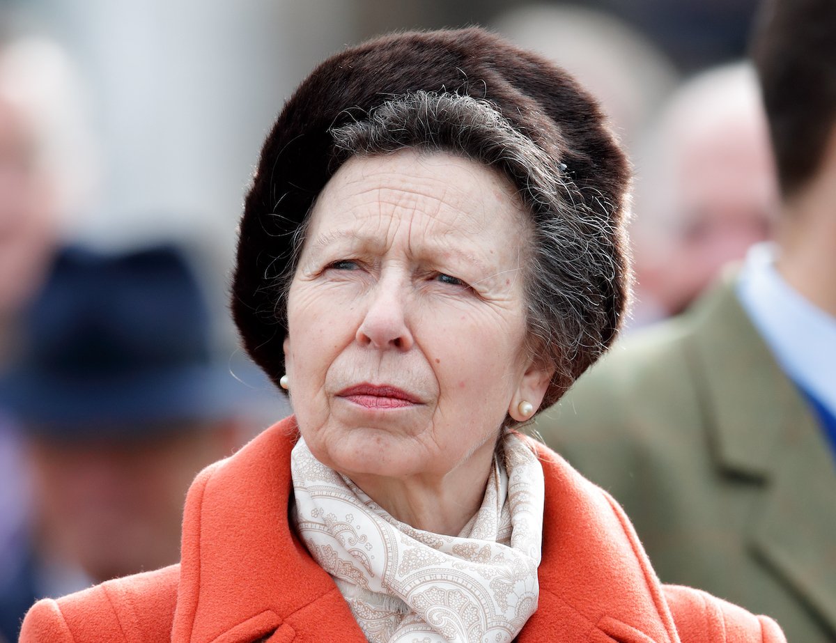 Princess Anne looking off to the site wearing a white scarf and red coat