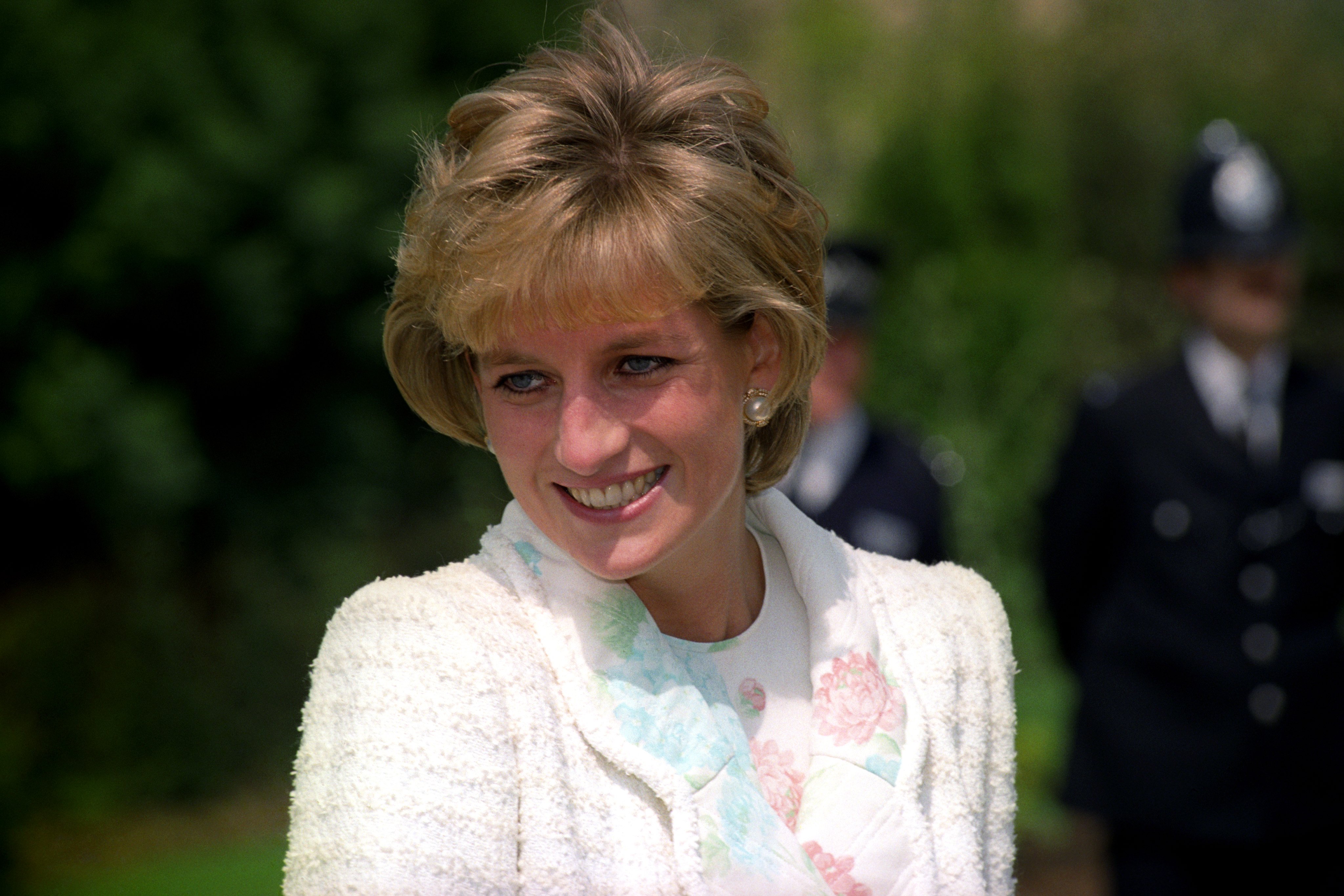 Princess Diana smiling and dressed in a pastel coat and shirt at the International Spinal Research Trust charity event