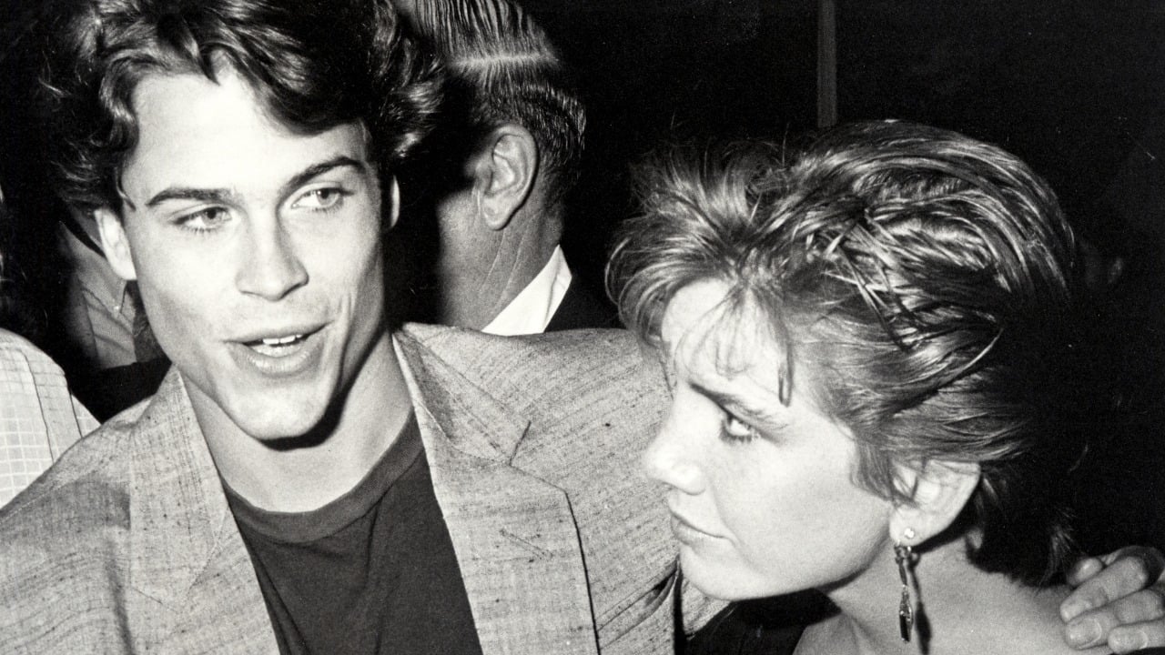 Rob Lowe and Melissa Gilbert in black and white. Lowe has his arm around Gilbert, and she's looking at him while he speaks.