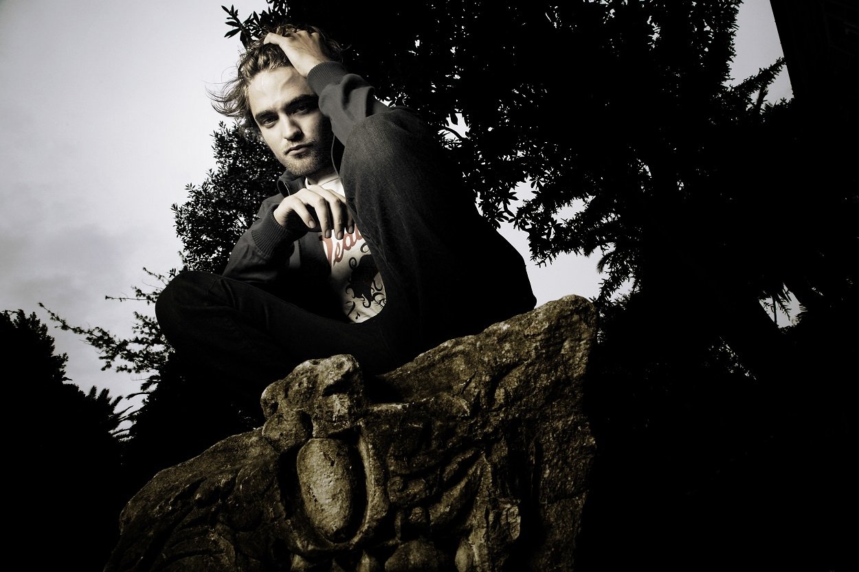 Twilight movies star Robert Pattinson squats with a hand in his hair as he poses for cast portraits