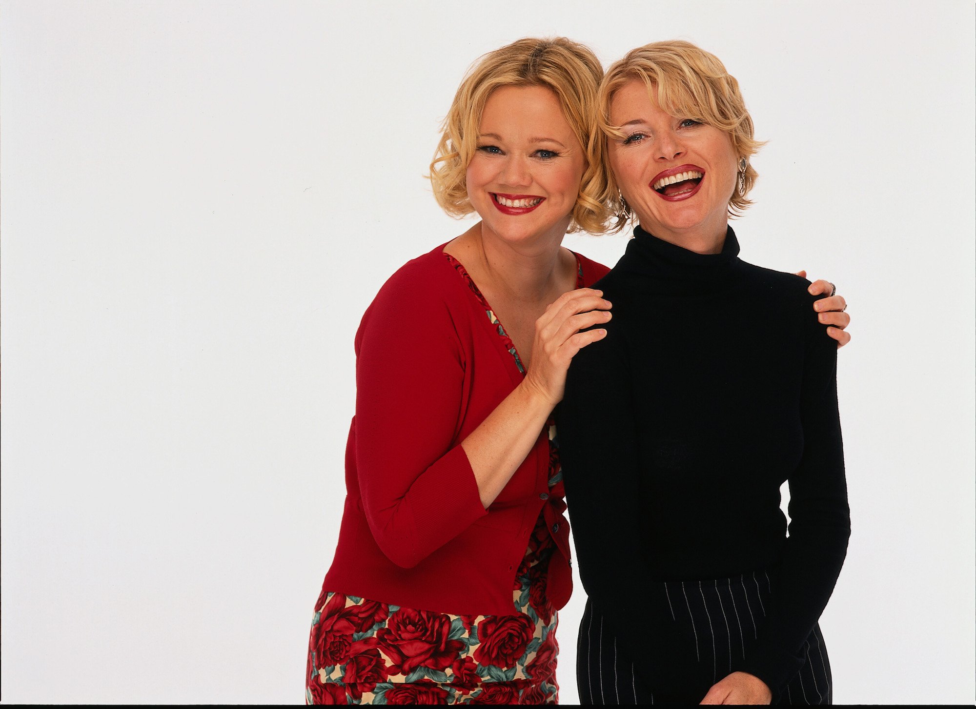 Caroline Rhea and Beth Broderick smiling in front of a white background