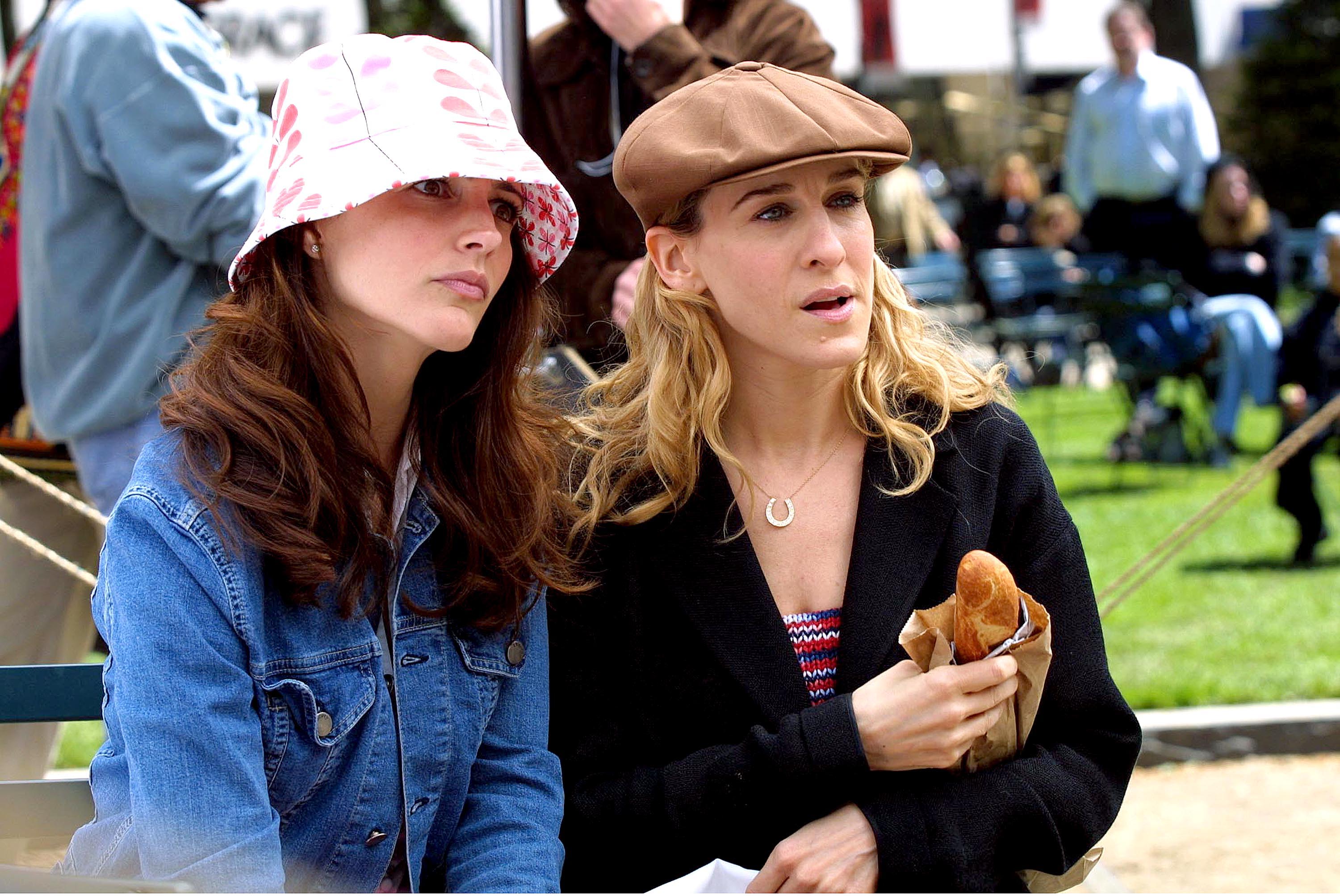 Kristin Davis as Charlotte York and Sarah Jessica Parker as Carrie Bradshsaw sitting on a bench in Central Park during a scene for 'Sex and the City' in 2001