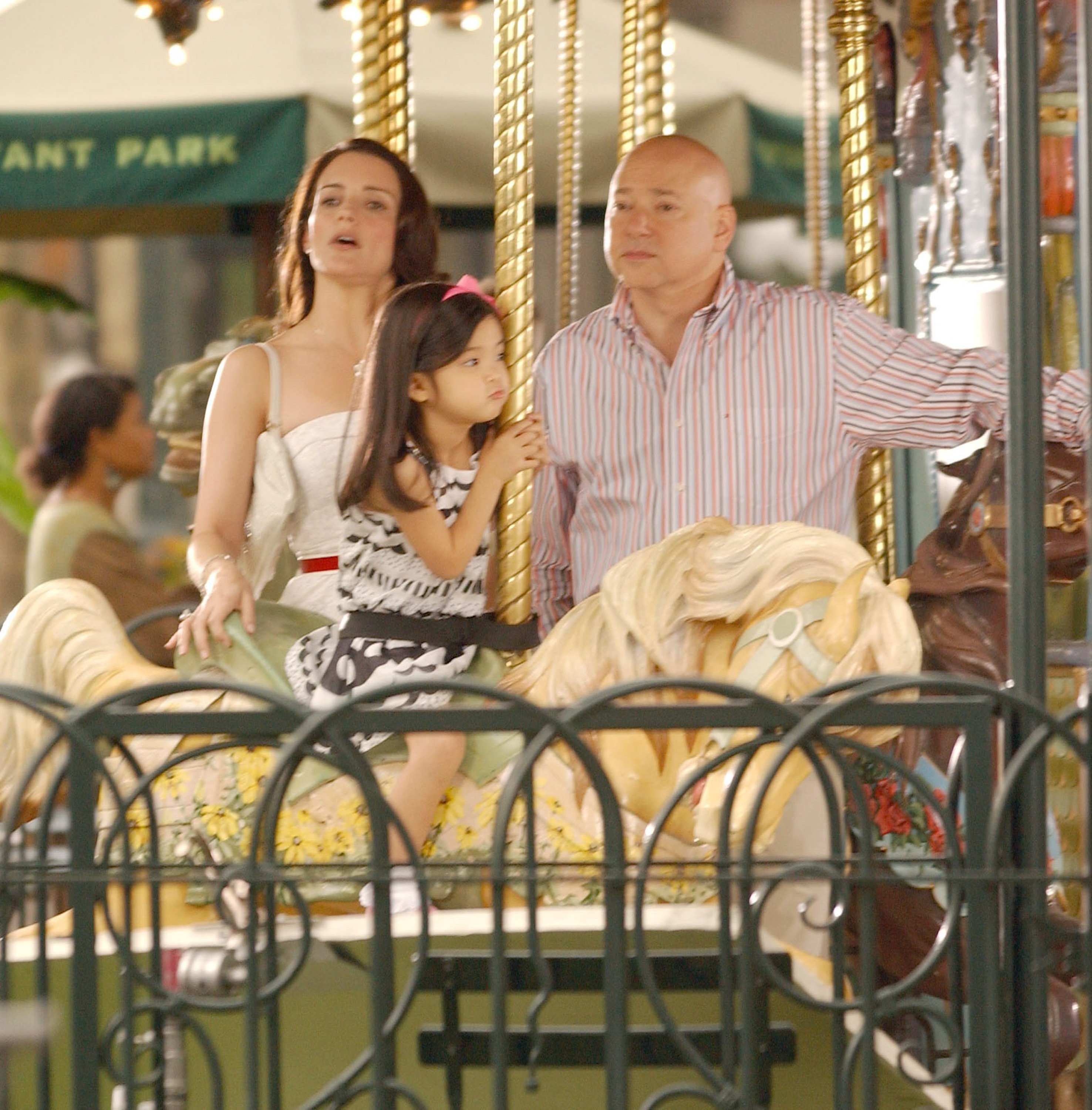 Kristin Davis and Evan Handler are photographed standing on Le Carrousel in Bryant Park with their on-screen daughter during the filming of 'Sex and the City: The Movie'