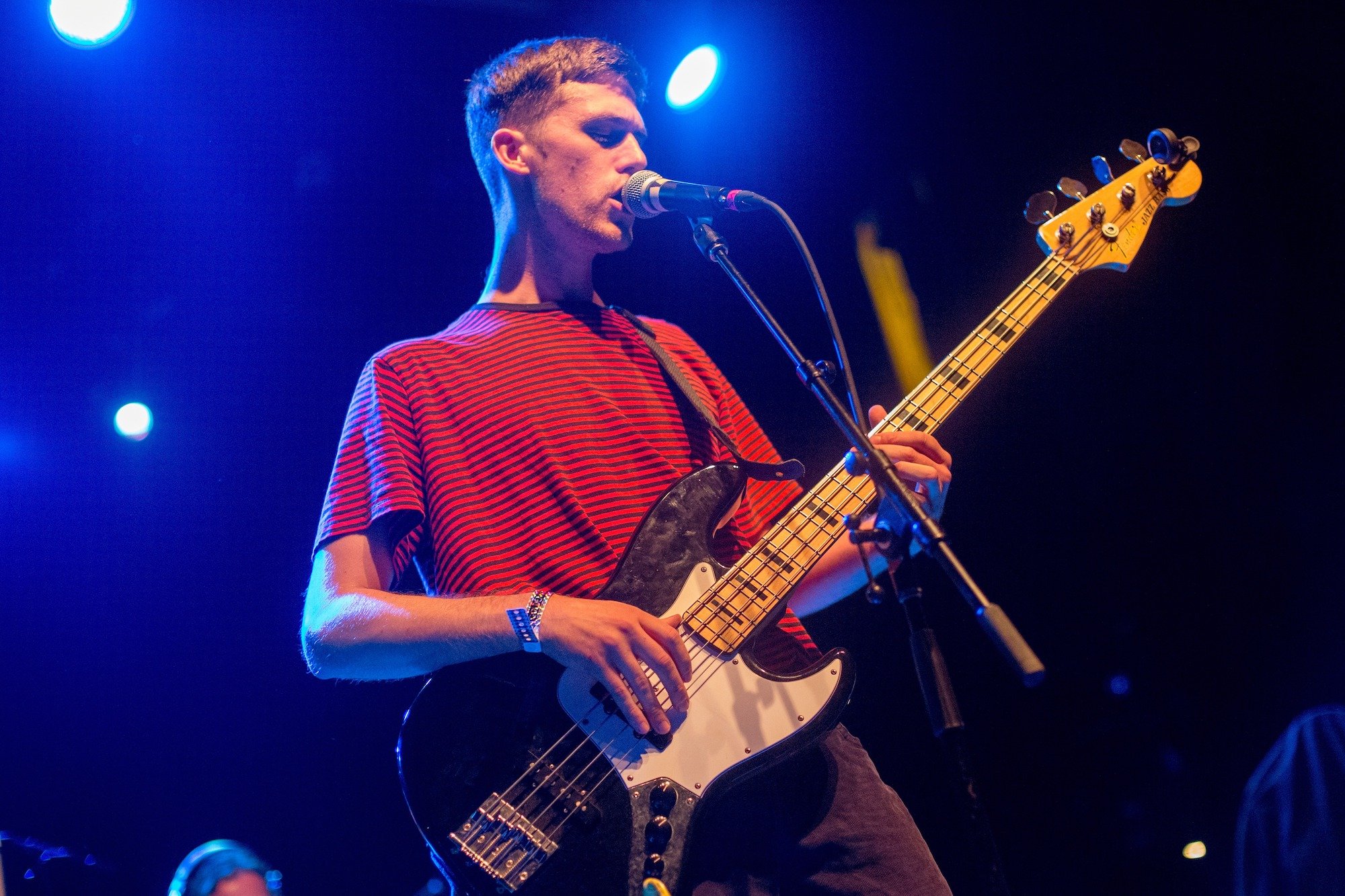 Sven Gamsky of Still Woozy singing into a microphone holding a guitar