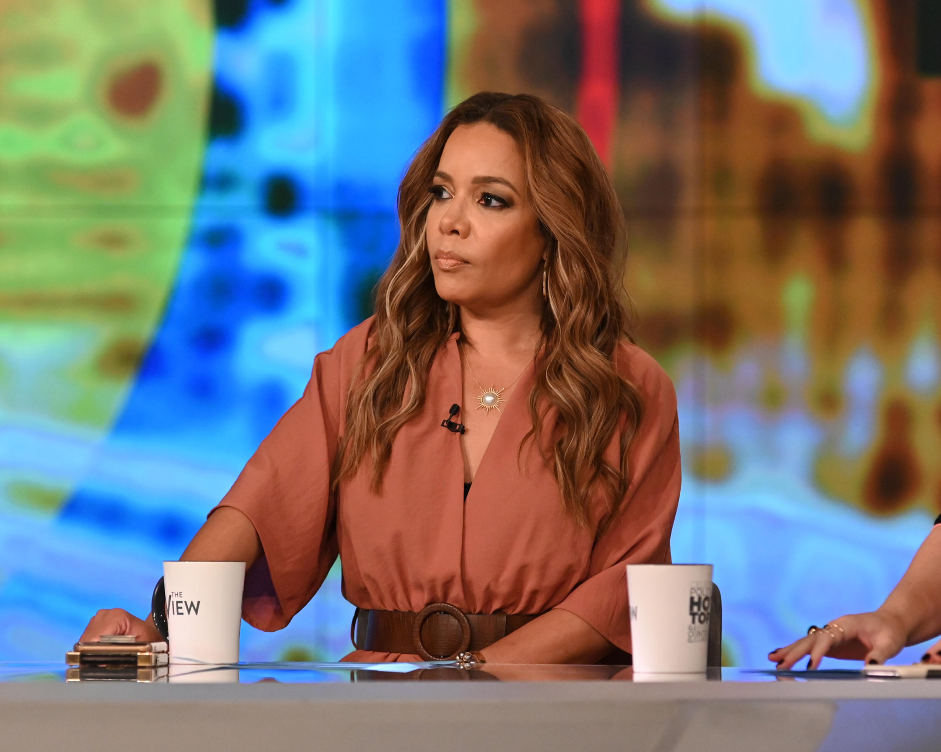 Sunny Hostin in a brown top at the desk of 'The View'